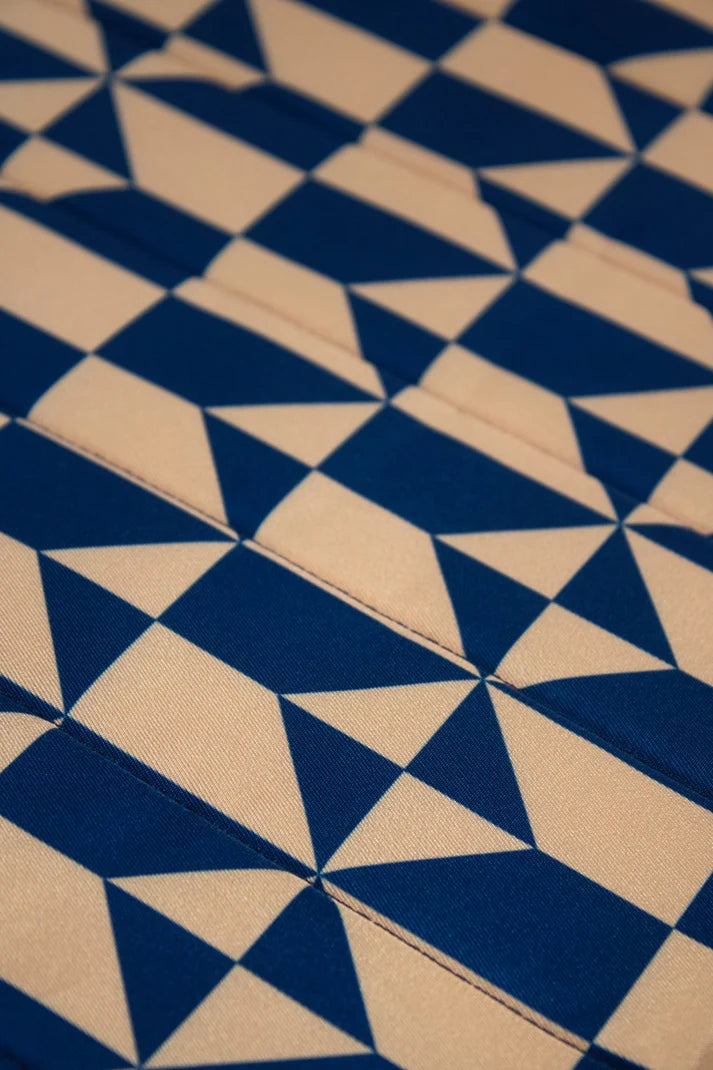 Close-up of fabric with a geometric pattern of intersecting beige and navy blue triangles.