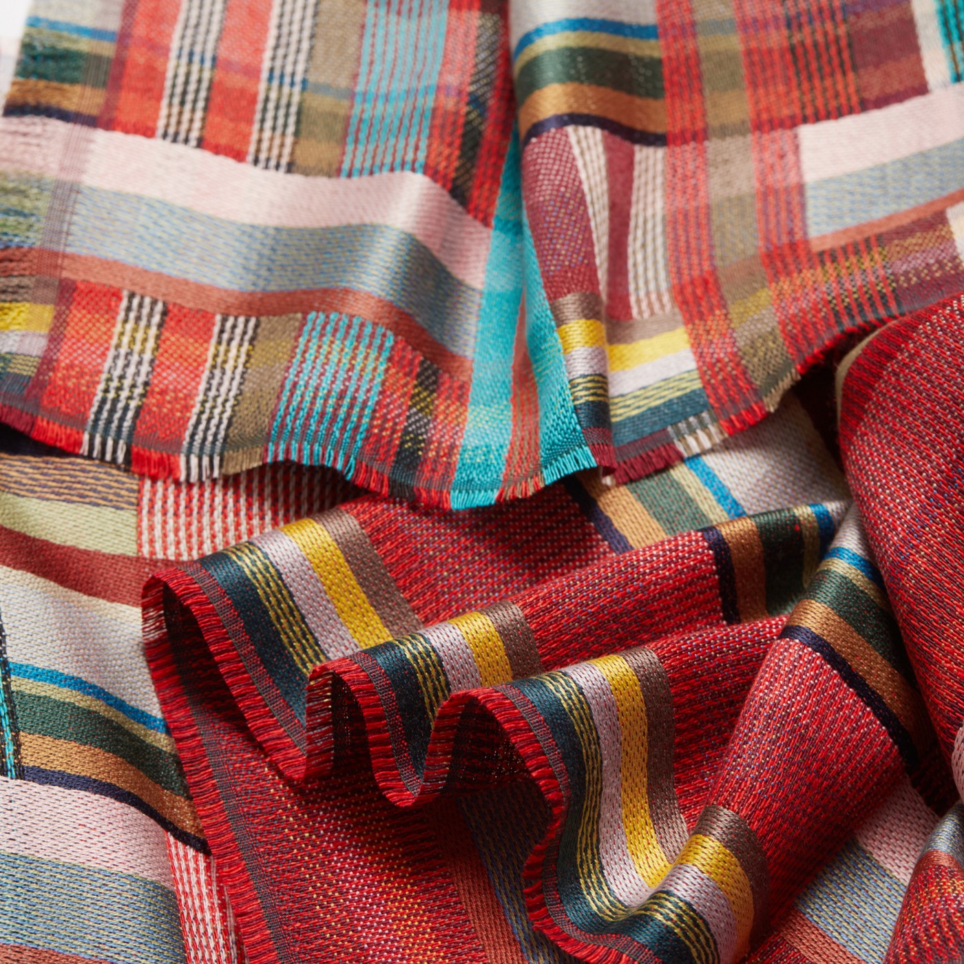 Red, teal, and beige woven fabric with a multicolored plaid pattern.