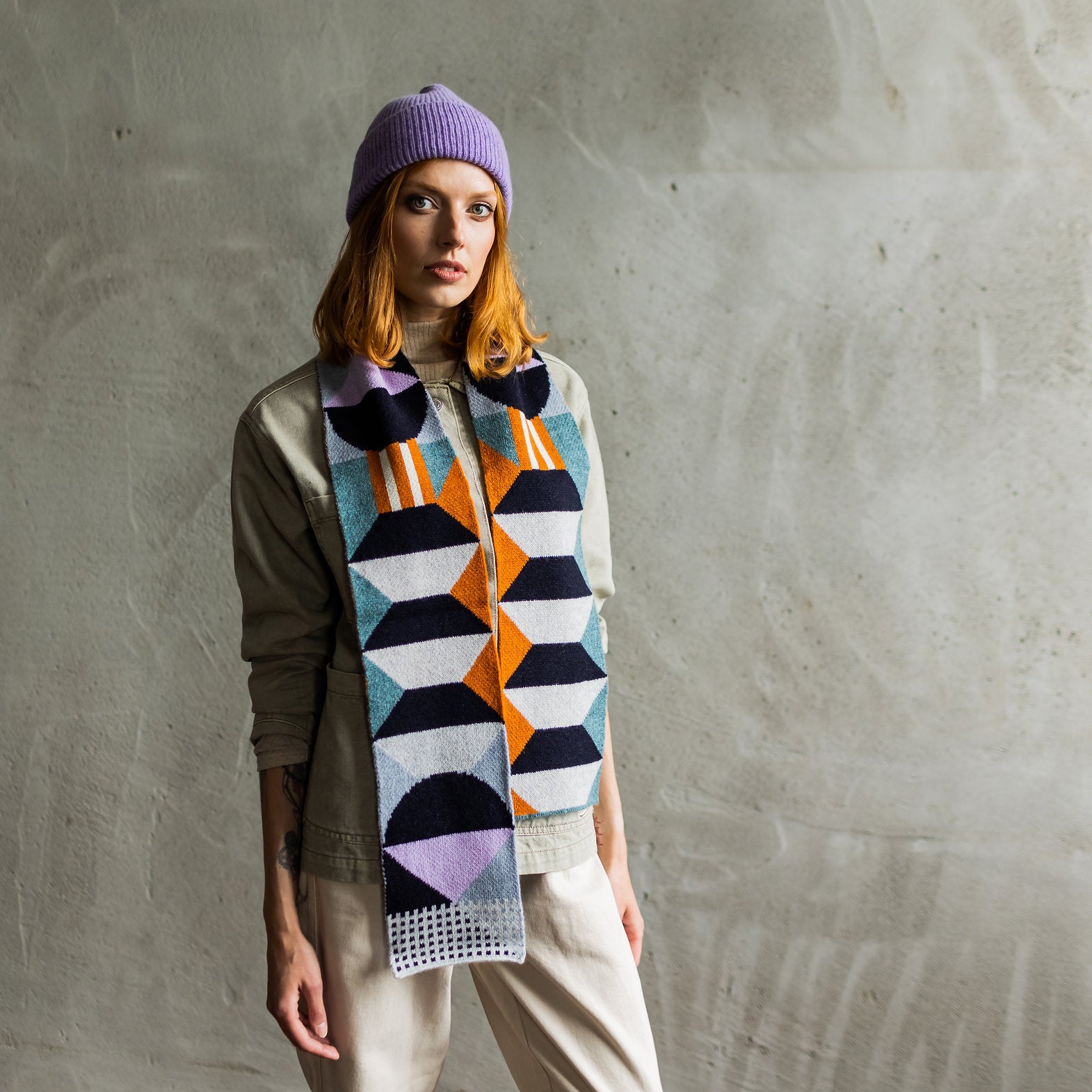 Geometric patterned knit scarf in teal, orange, black, and lavender.
