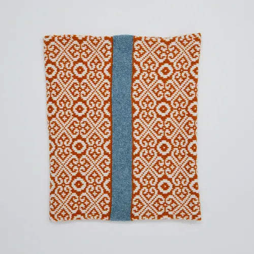 Rust-colored knitted neck warmer with a central teal stripe and an intricate geometric pattern.
