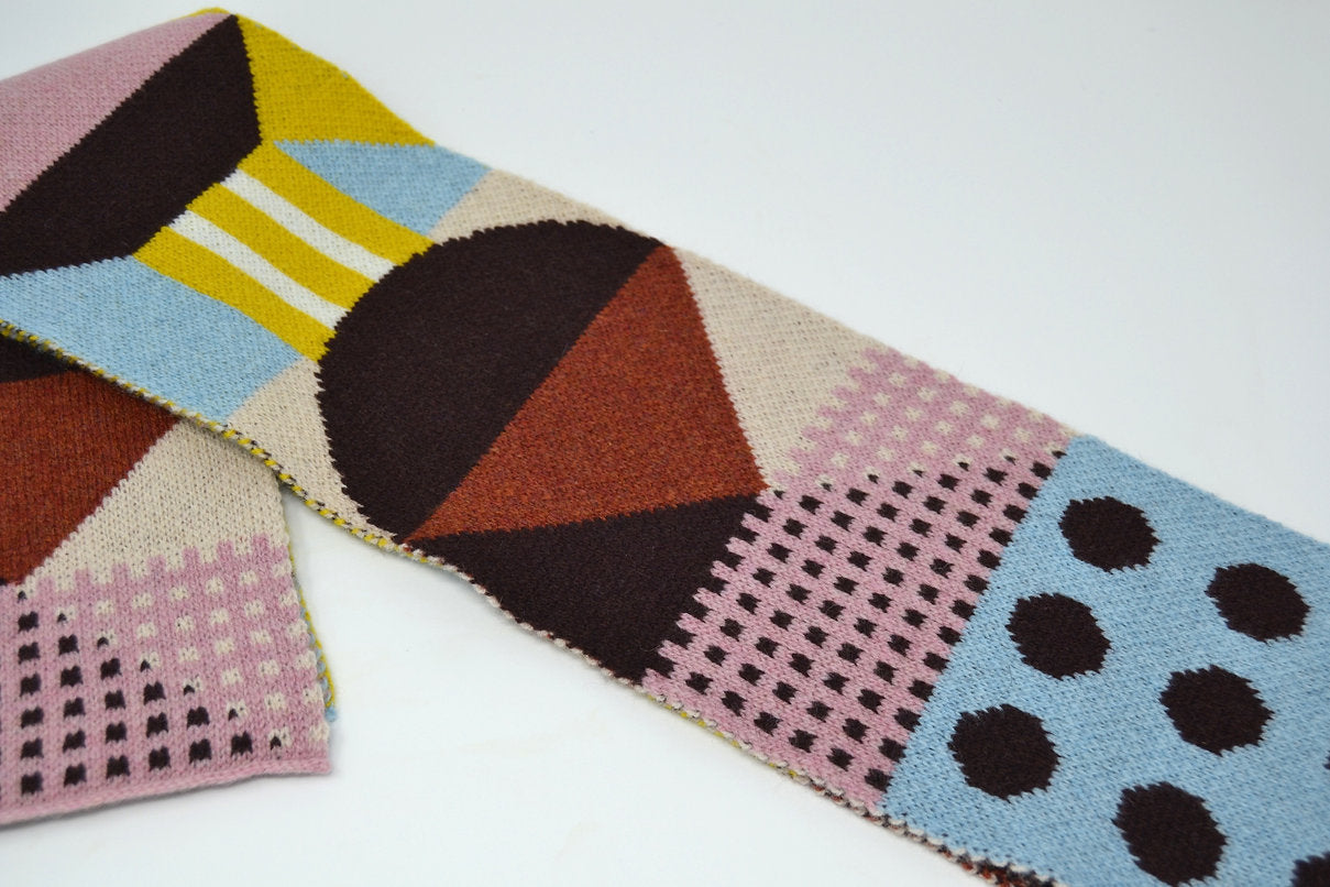 Geometric patterned knit scarf in brown, beige, pink, and blue.