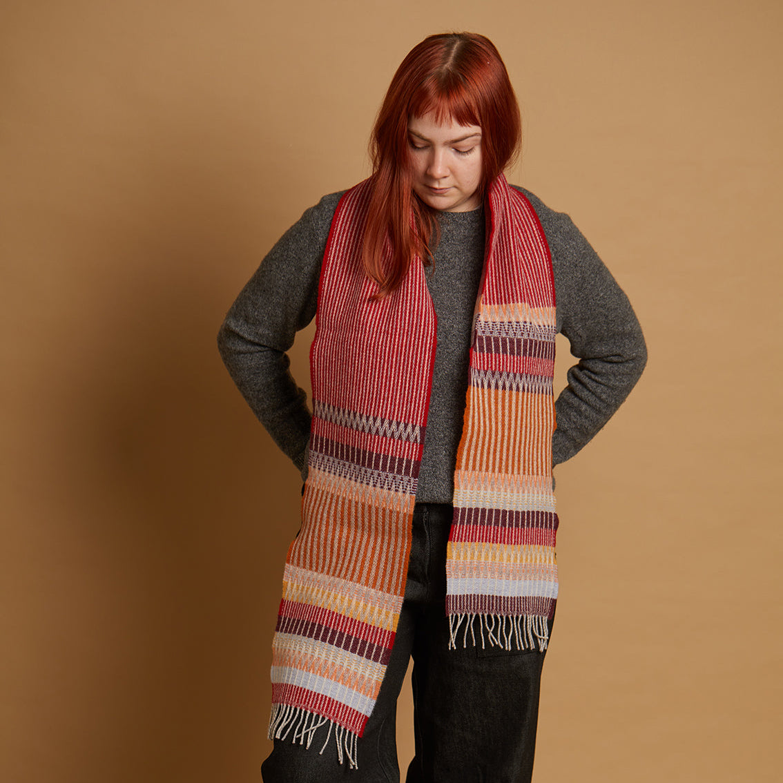 Person wearing a colorful striped scarf against a beige background
