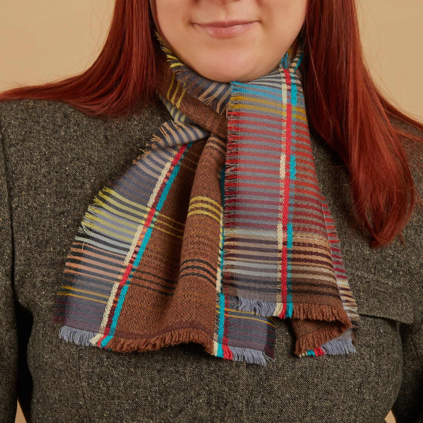 Person wearing a colorful plaid scarf with a neutral background