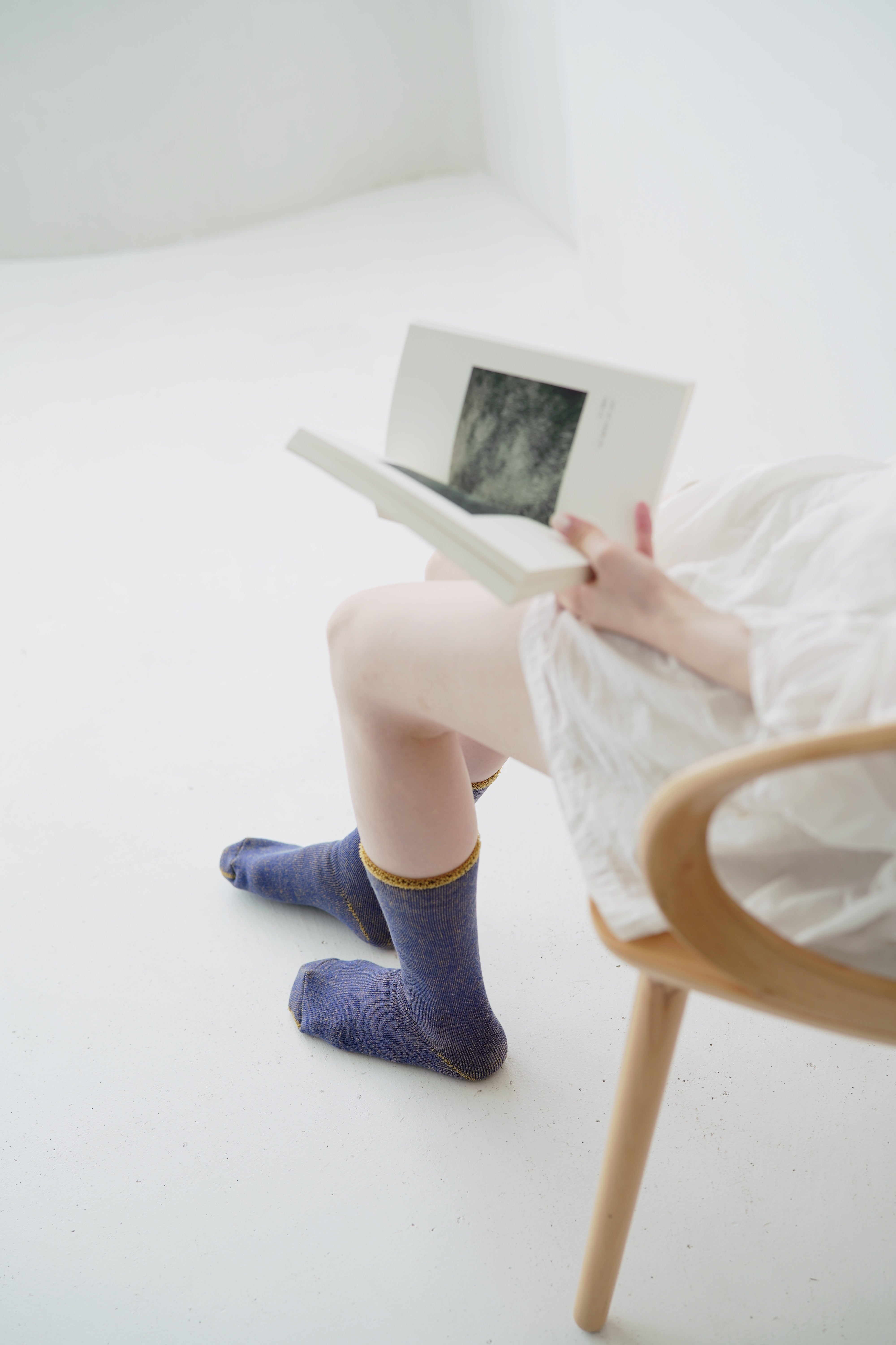 Pair of purple ribbed socks with gold accents, worn by a person sitting and reading a book.
