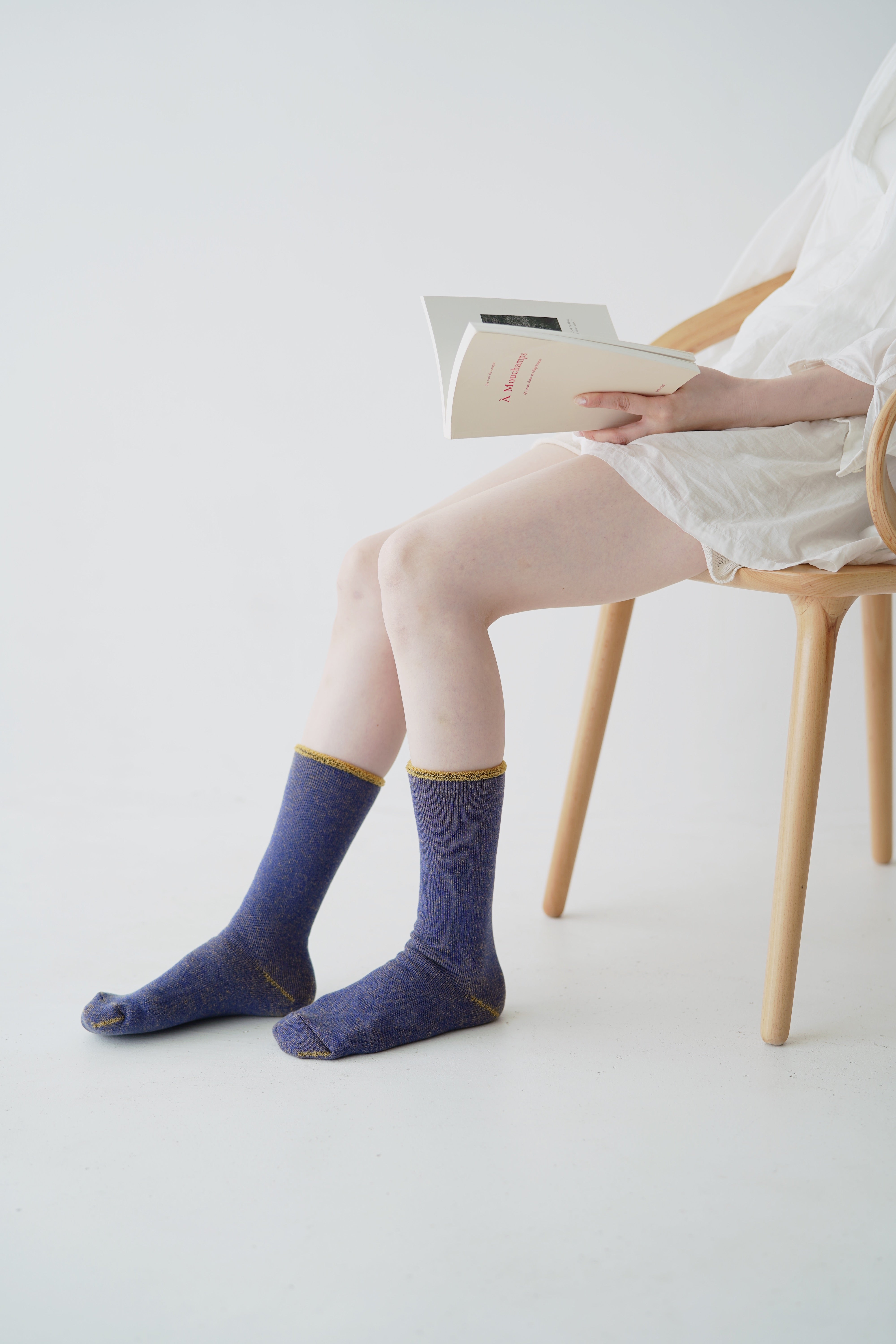 Pair of purple socks with gold trim, worn by a person sitting in a wooden chair.