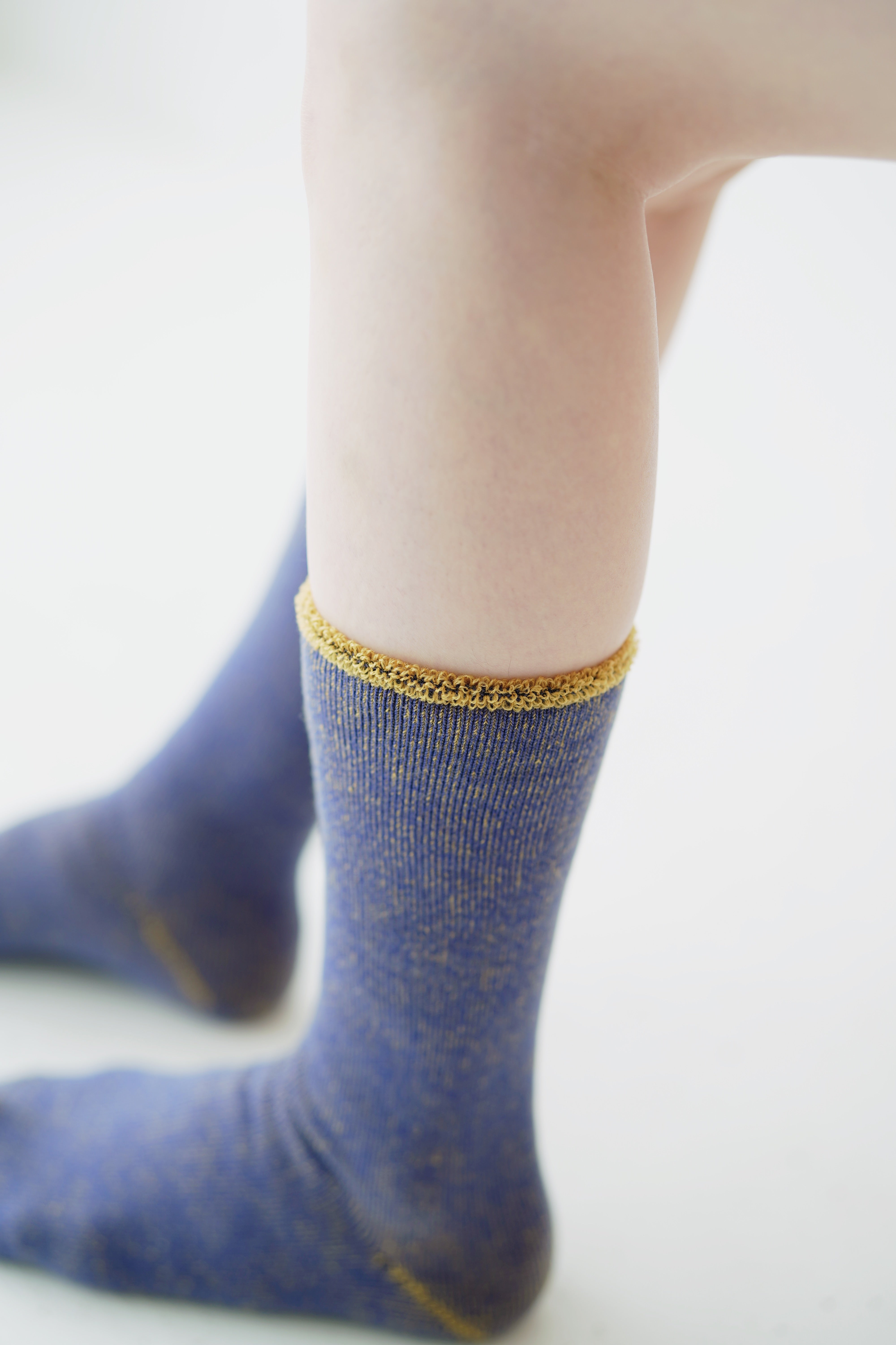 Pair of blue socks with gold speckled pattern and gold top trim.