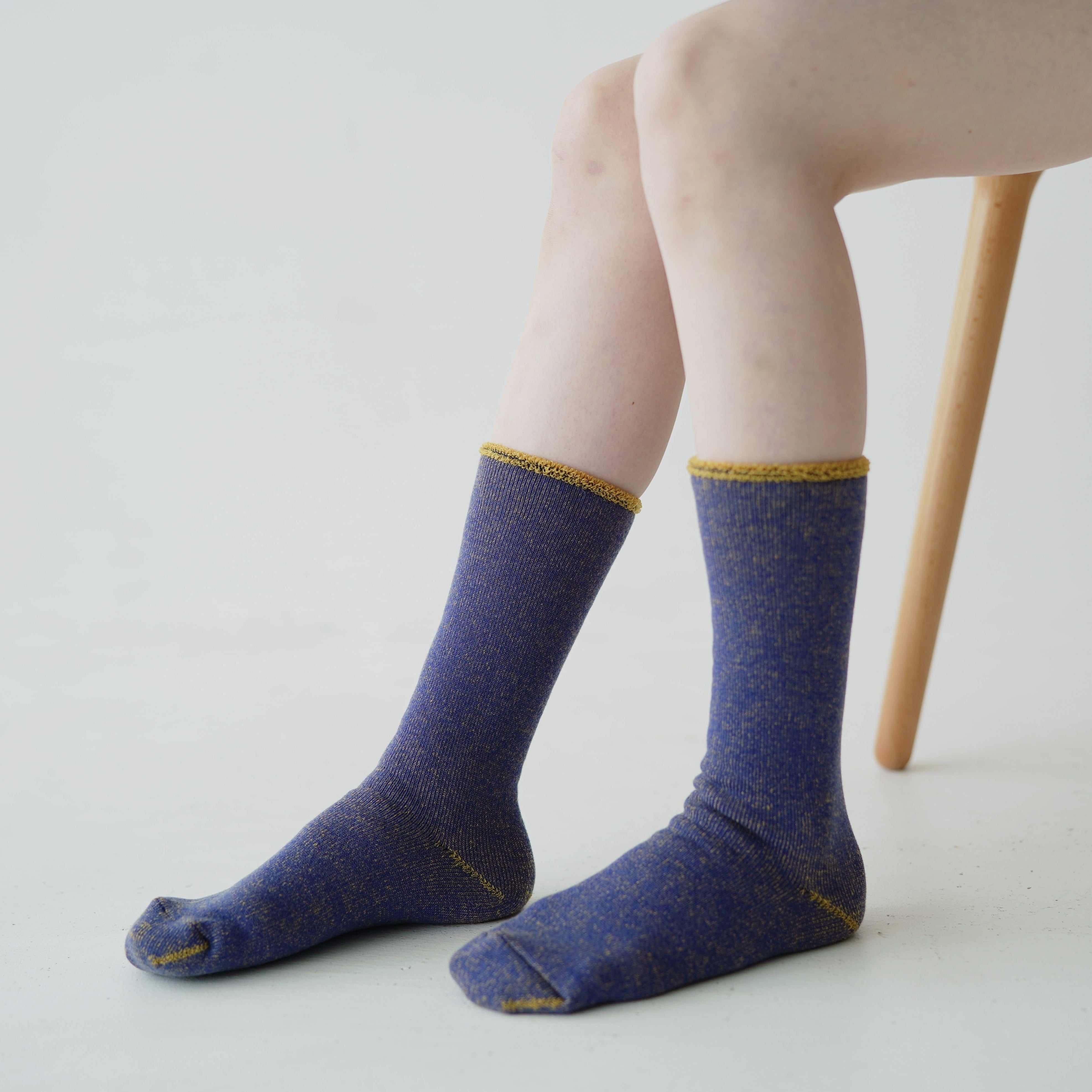 Pair of blue crew socks with gold flecks and trim.