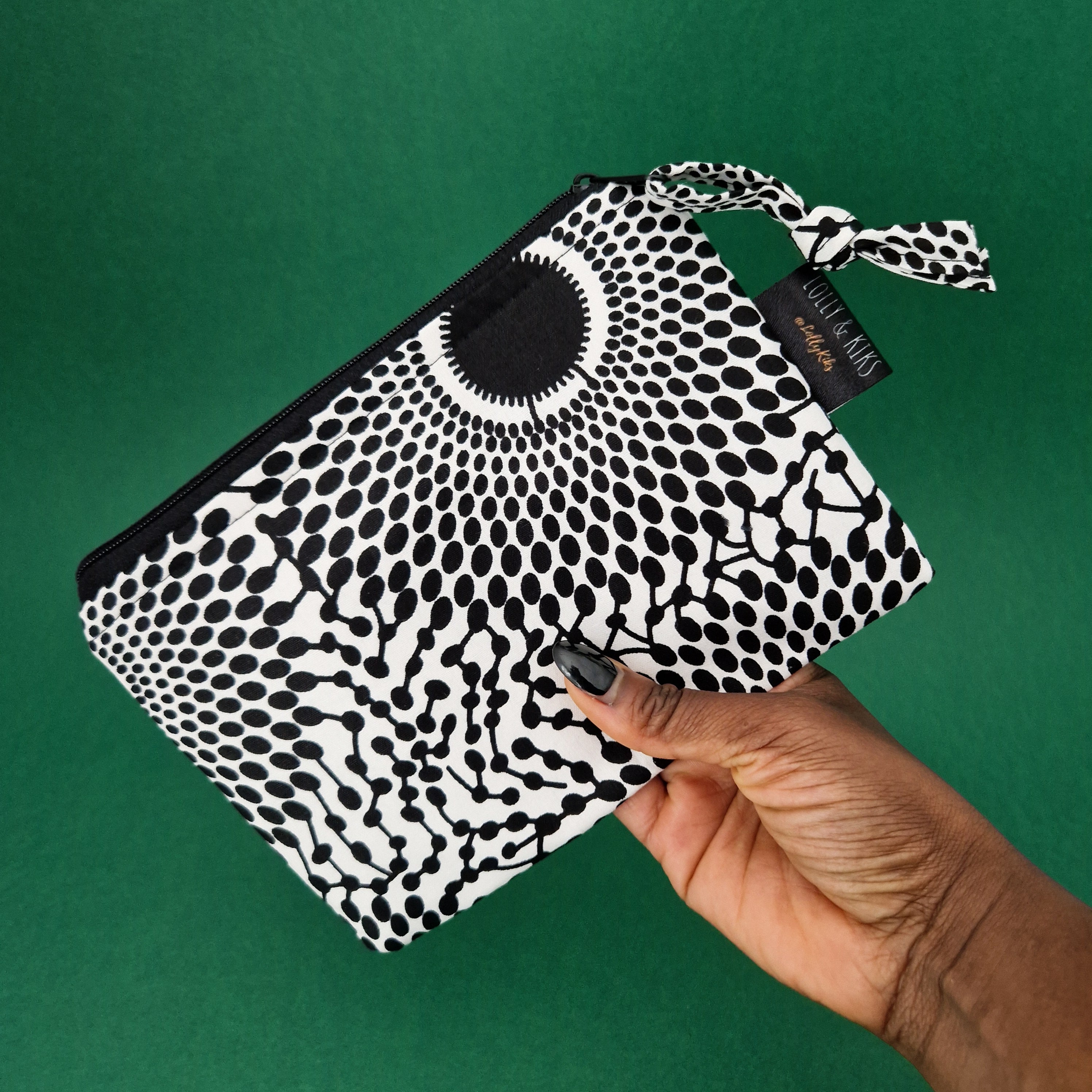 Black and white patterned zippered pouch held in a hand.