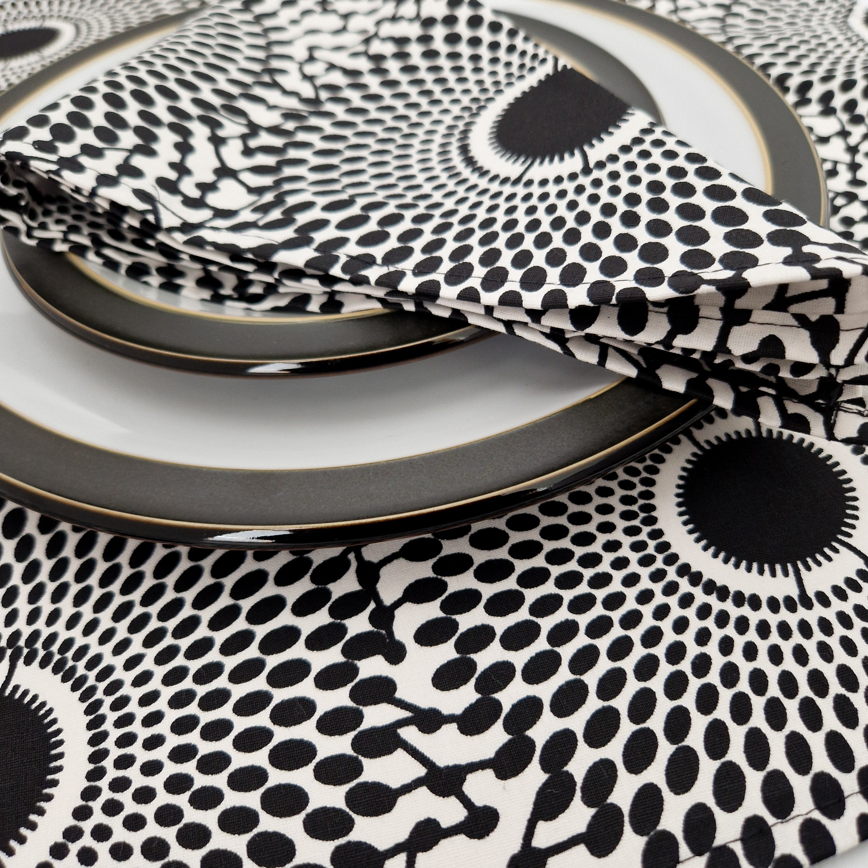 Black and white patterned fabric napkin folded on dark gray and white plates.