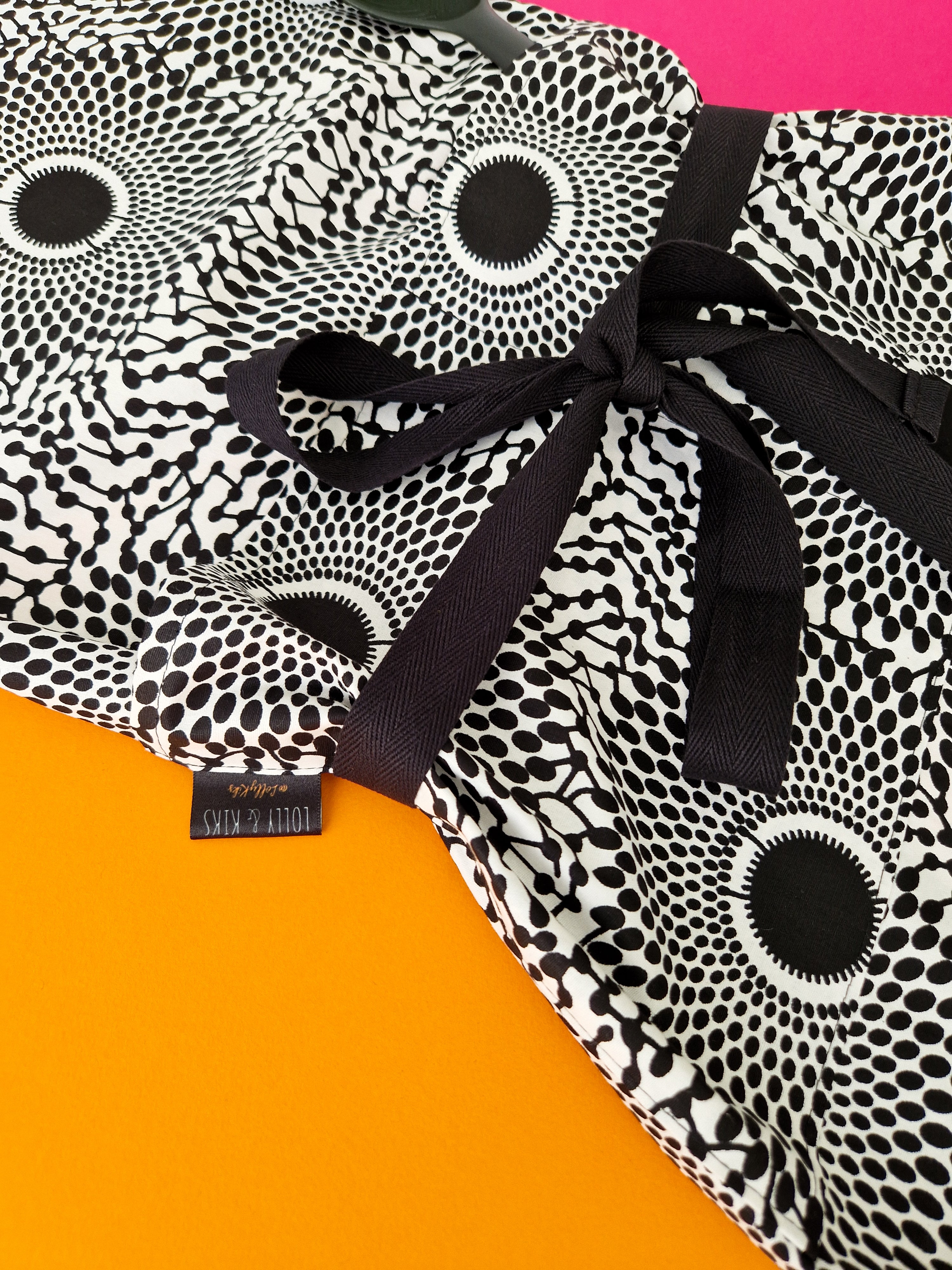 Black and white patterned dress with a black tie waist. The pattern features radiating circles of varying sizes.