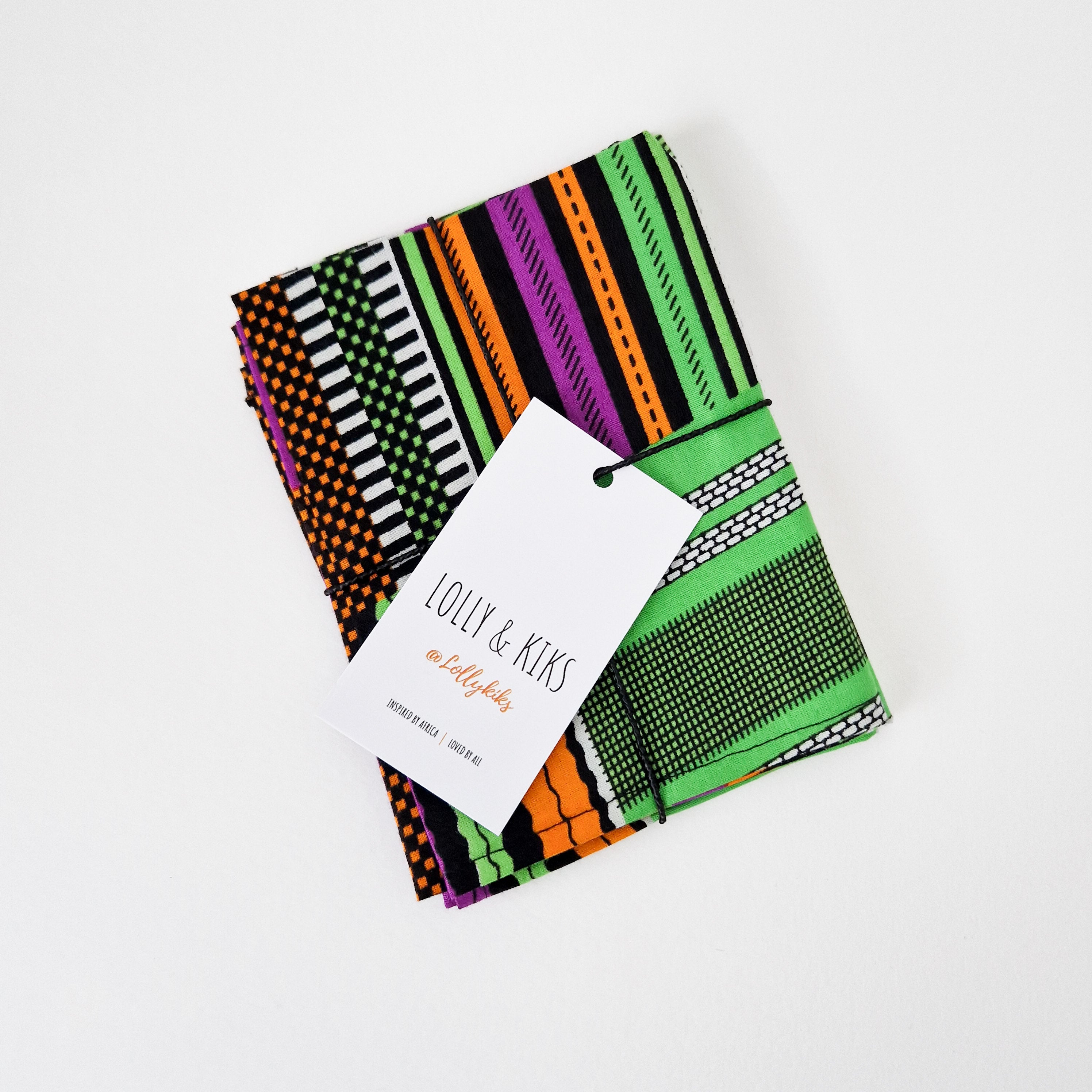 Stack of colorful striped fabric napkins tied with twine and a Lolly & Kiks brand tag.