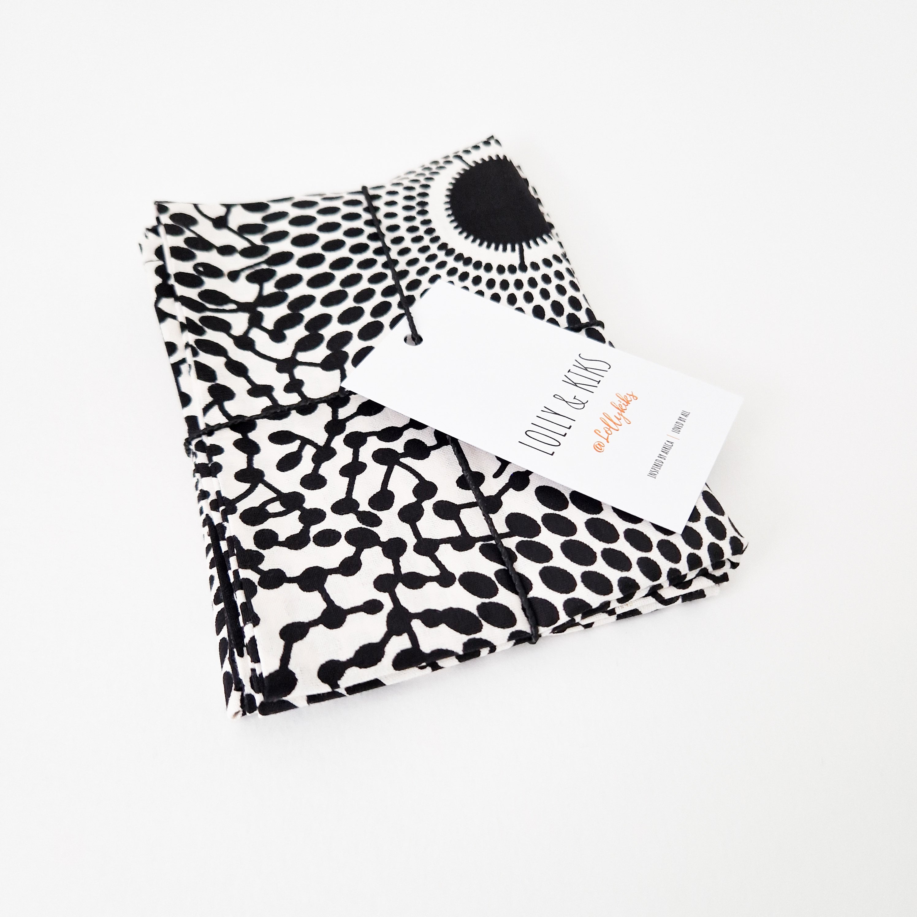 Black and white fabric bundle with a repeating dot and line pattern, tied with string, and featuring a product tag.
