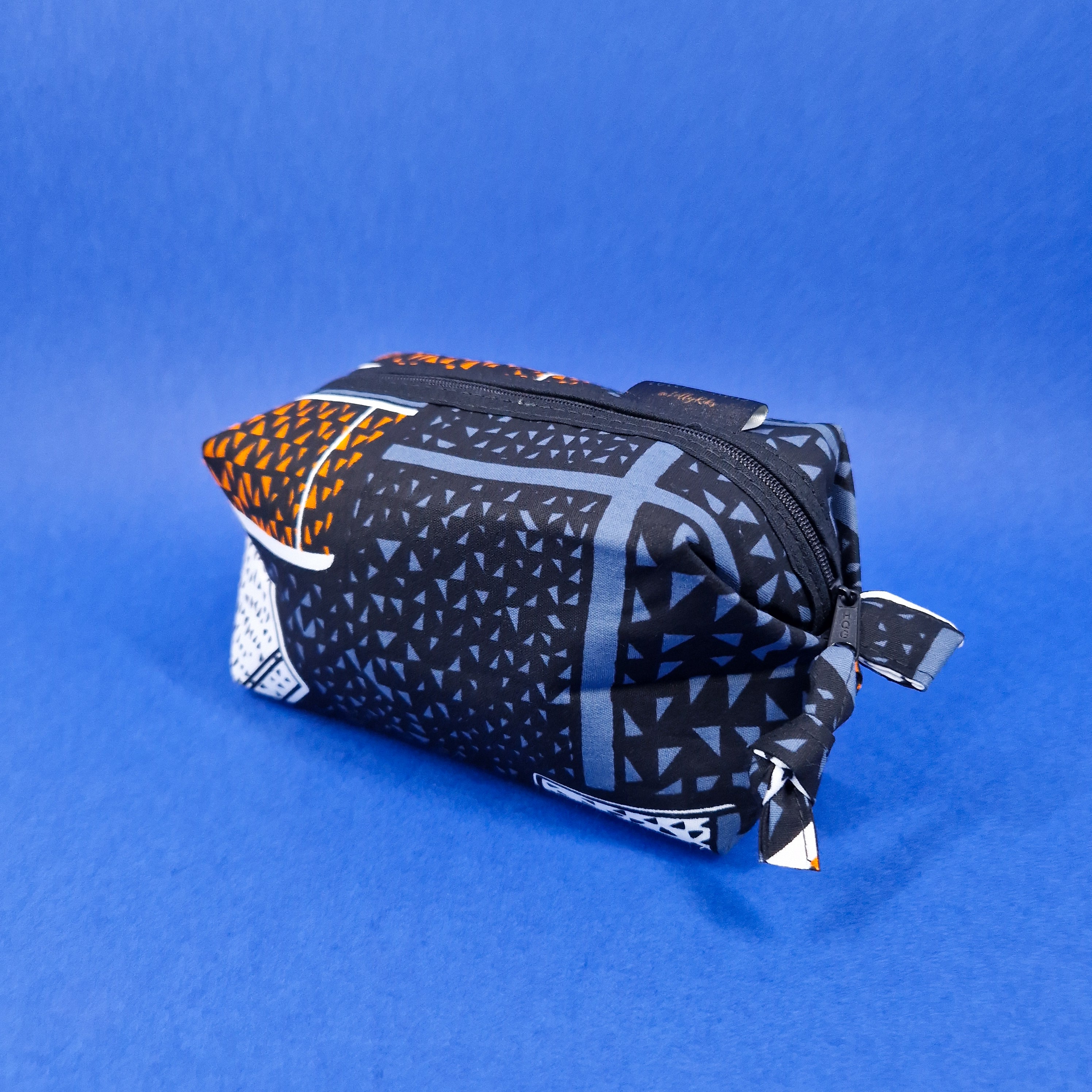 Black and gray geometric patterned zippered pouch with orange accents.