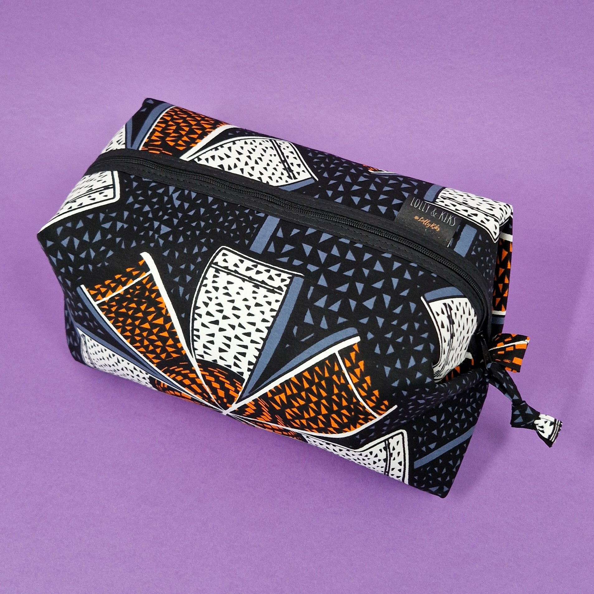 Rectangular zippered pouch with black background and orange, white, and blue geometric print.