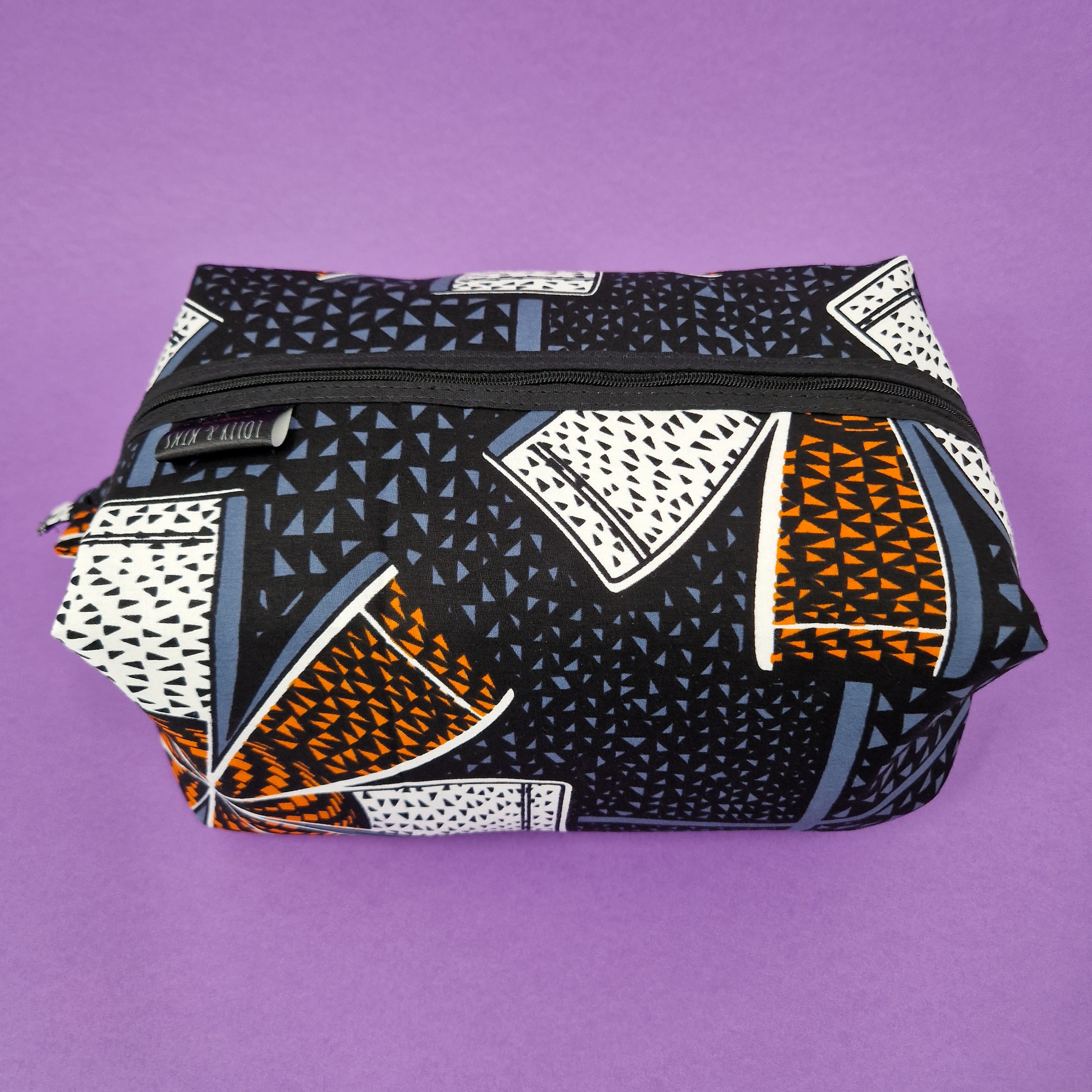 Rectangular zippered pouch with a black, gray, white, and orange geometric print.