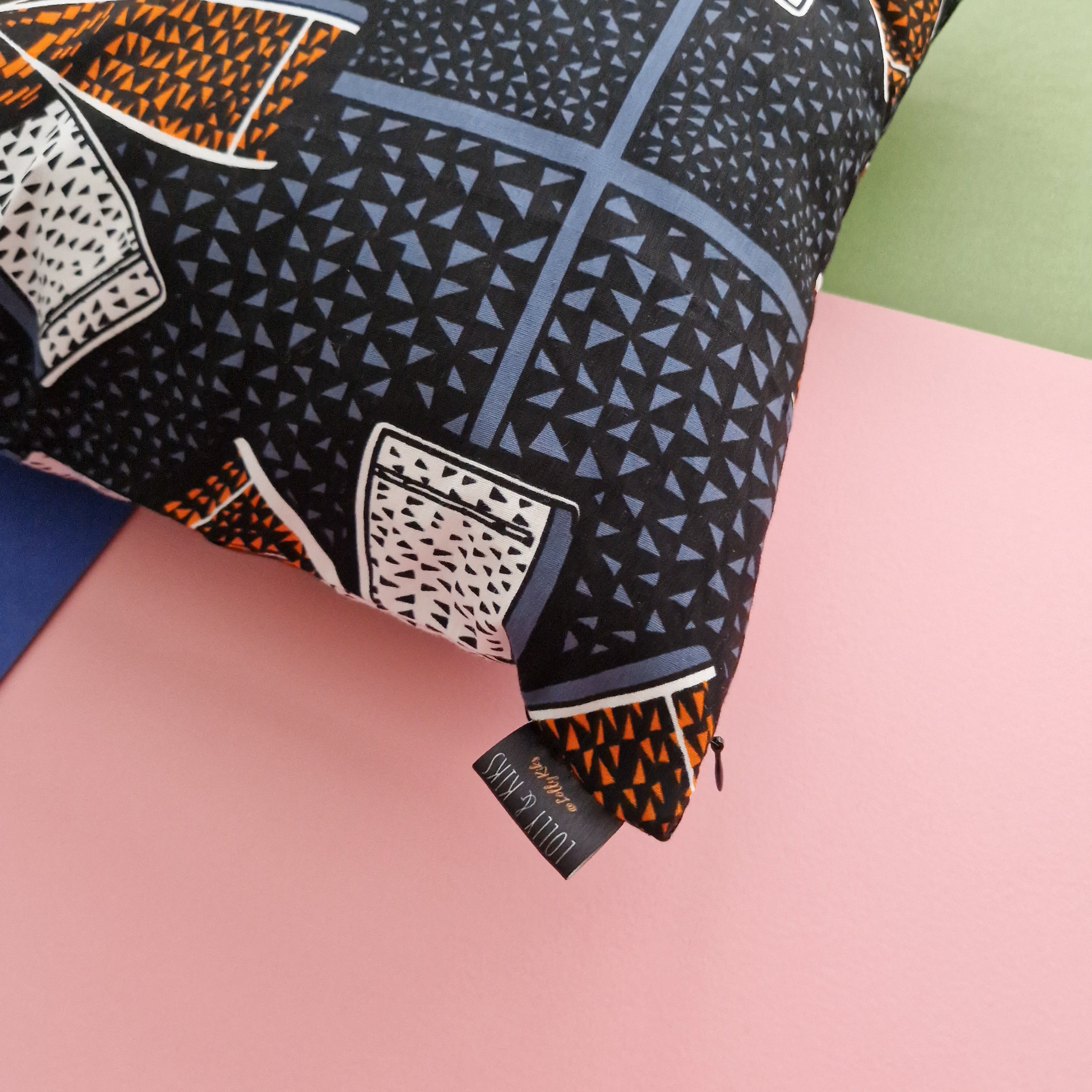 Decorative pillow with geometric pattern in black, orange, and blue tones.