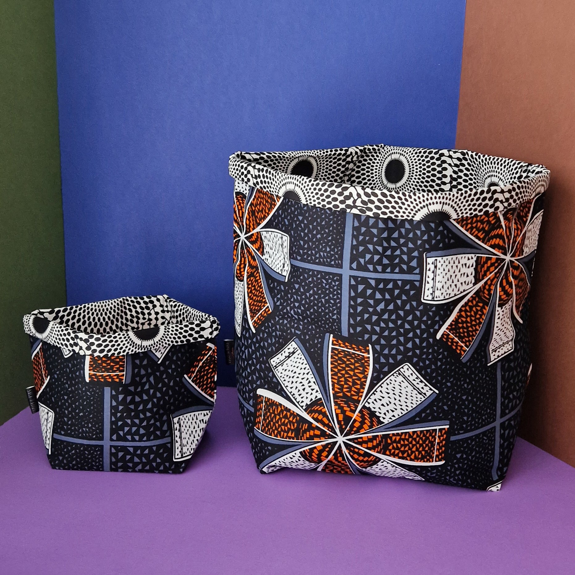 Two fabric storage baskets with a geometric African-inspired print in black, orange, white, and gray.