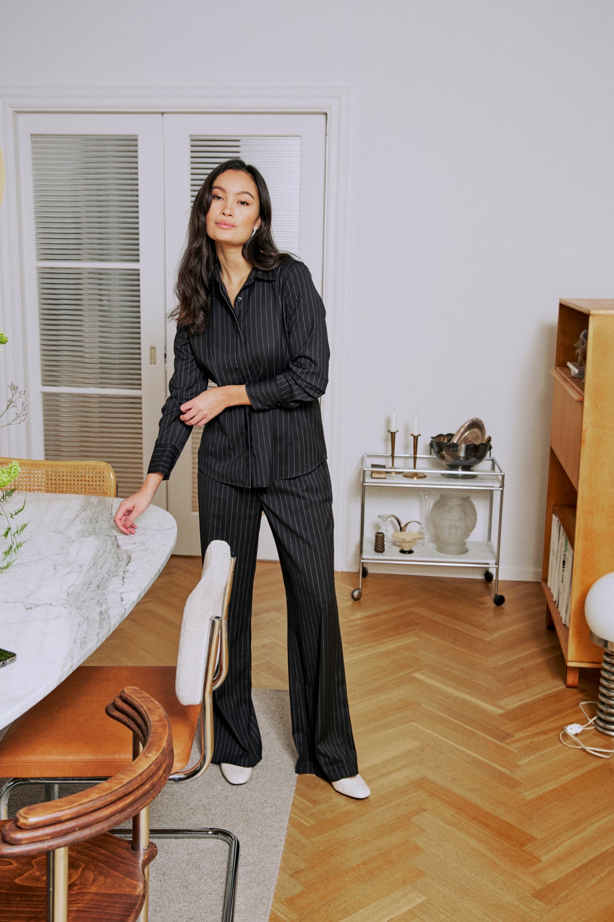 Black pinstripe pantsuit with a collared shirt and long sleeves.  The model is wearing white shoes.