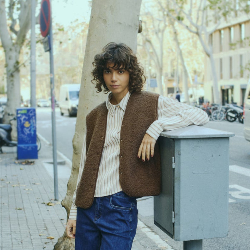 Person leaning against a street light on a city sidewalk