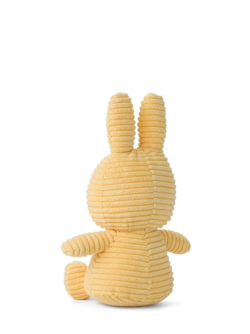 Pale yellow corduroy bunny plush toy, sitting, viewed from behind.