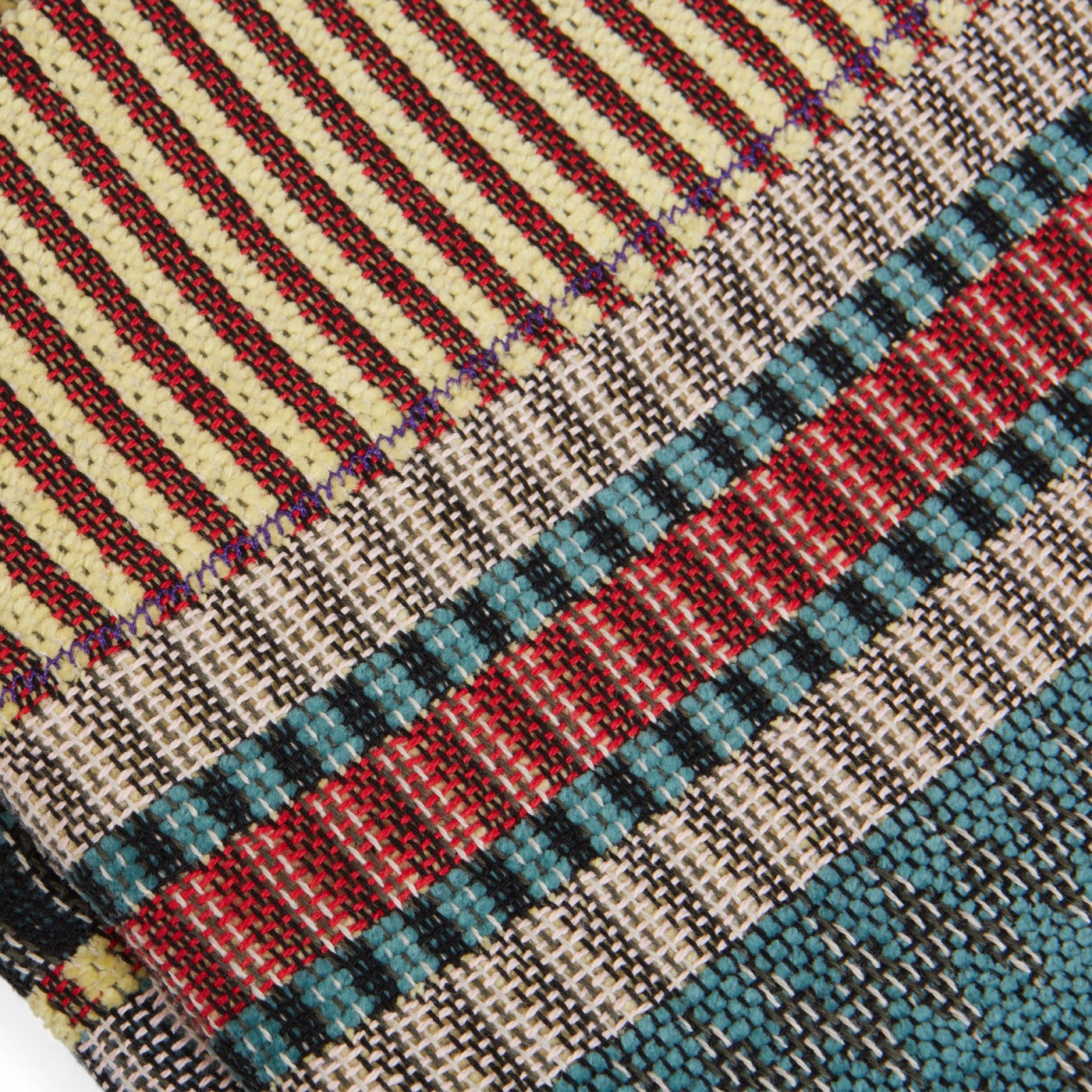 Close-up of multicolored woven fabric with stripes and textured patterns in red, teal, beige, and black.