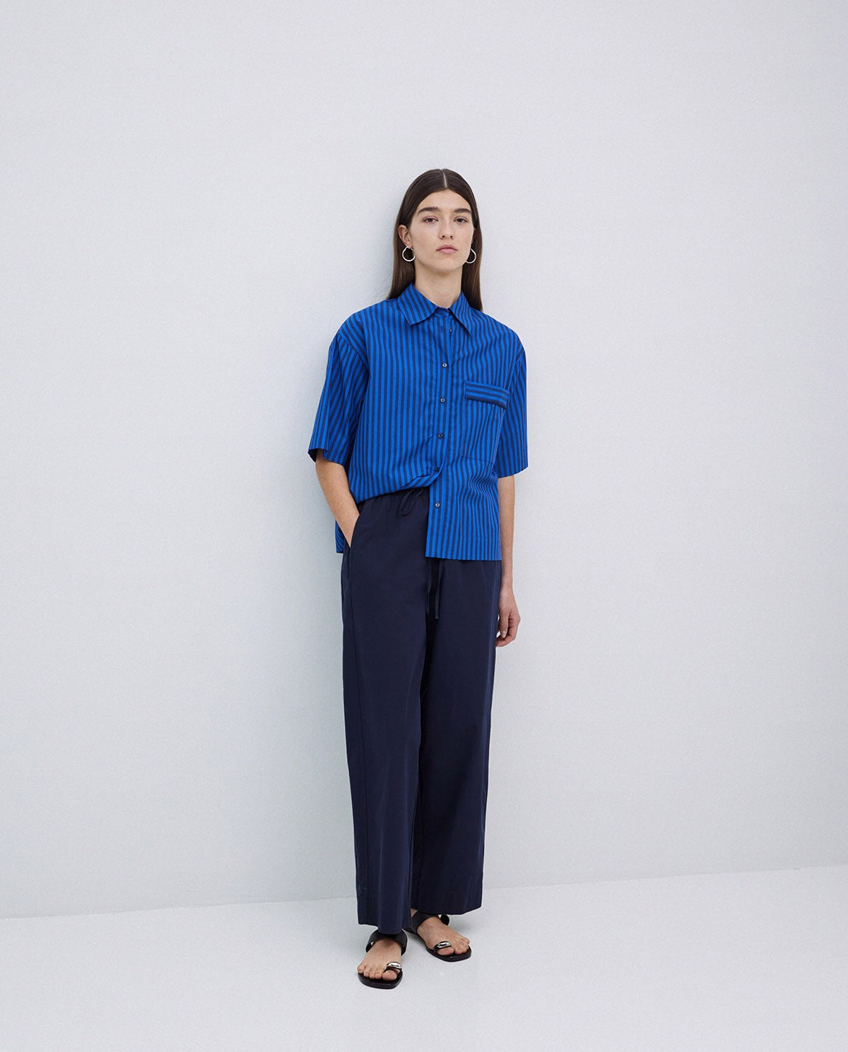 Blue striped short-sleeve shirt and dark navy wide-leg trousers.