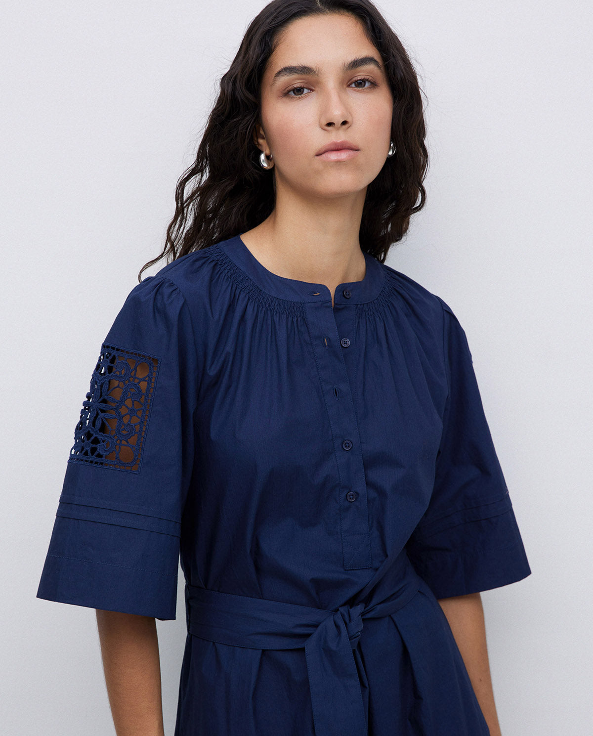 Navy blue belted dress with three-quarter sleeves and lace inset detailing on the upper sleeves.