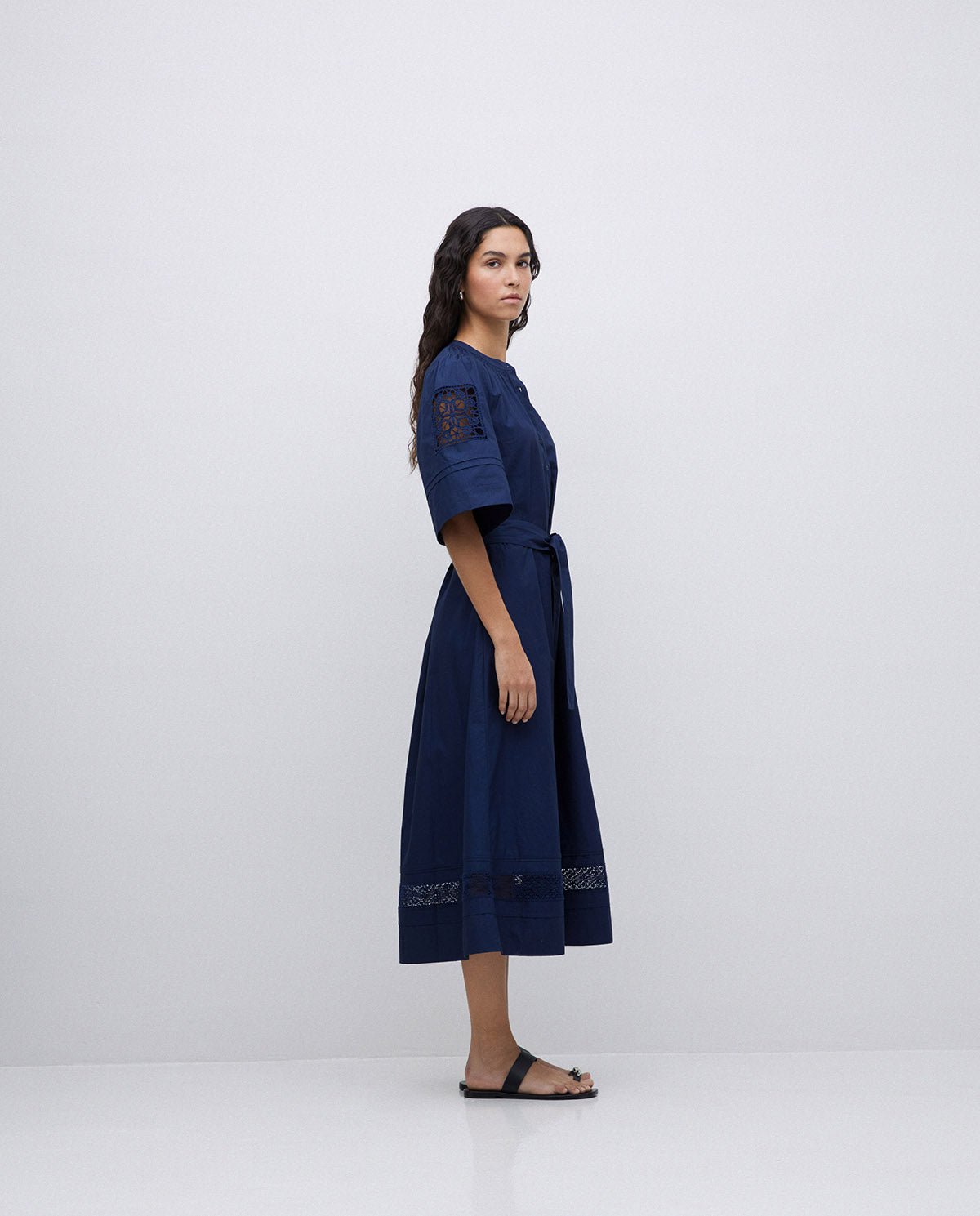 Navy midi dress with short sleeves, lace detailing at the shoulders and hem, and a self-tie belt.
