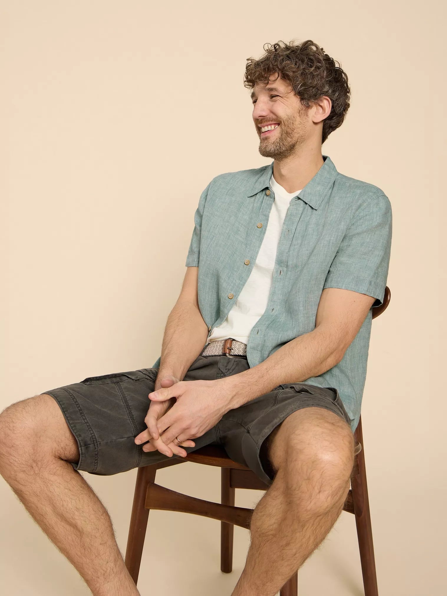Man wearing a teal linen short-sleeve shirt and dark gray cargo shorts.