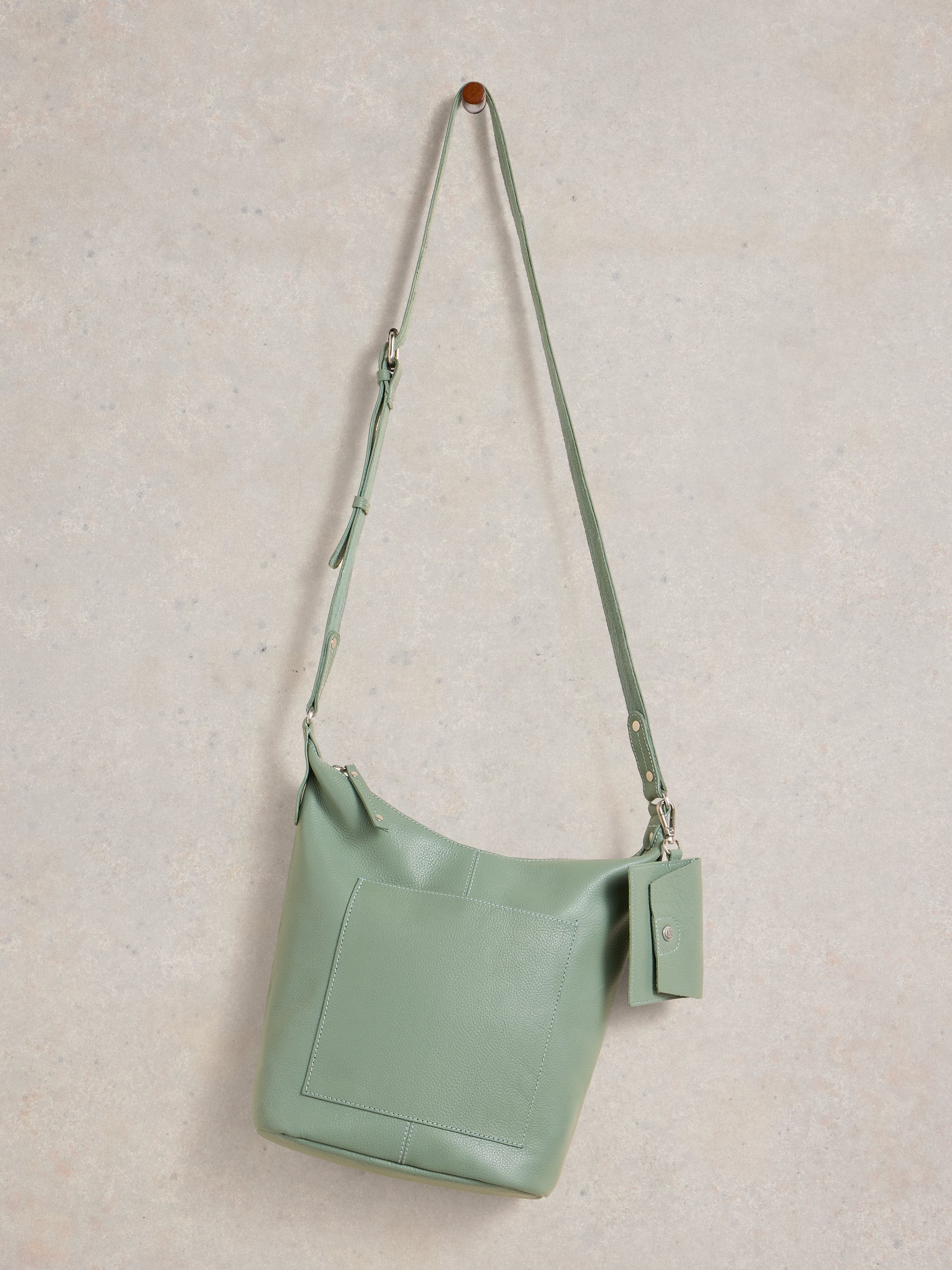 Mint green handbag with a strap on a light gray background
