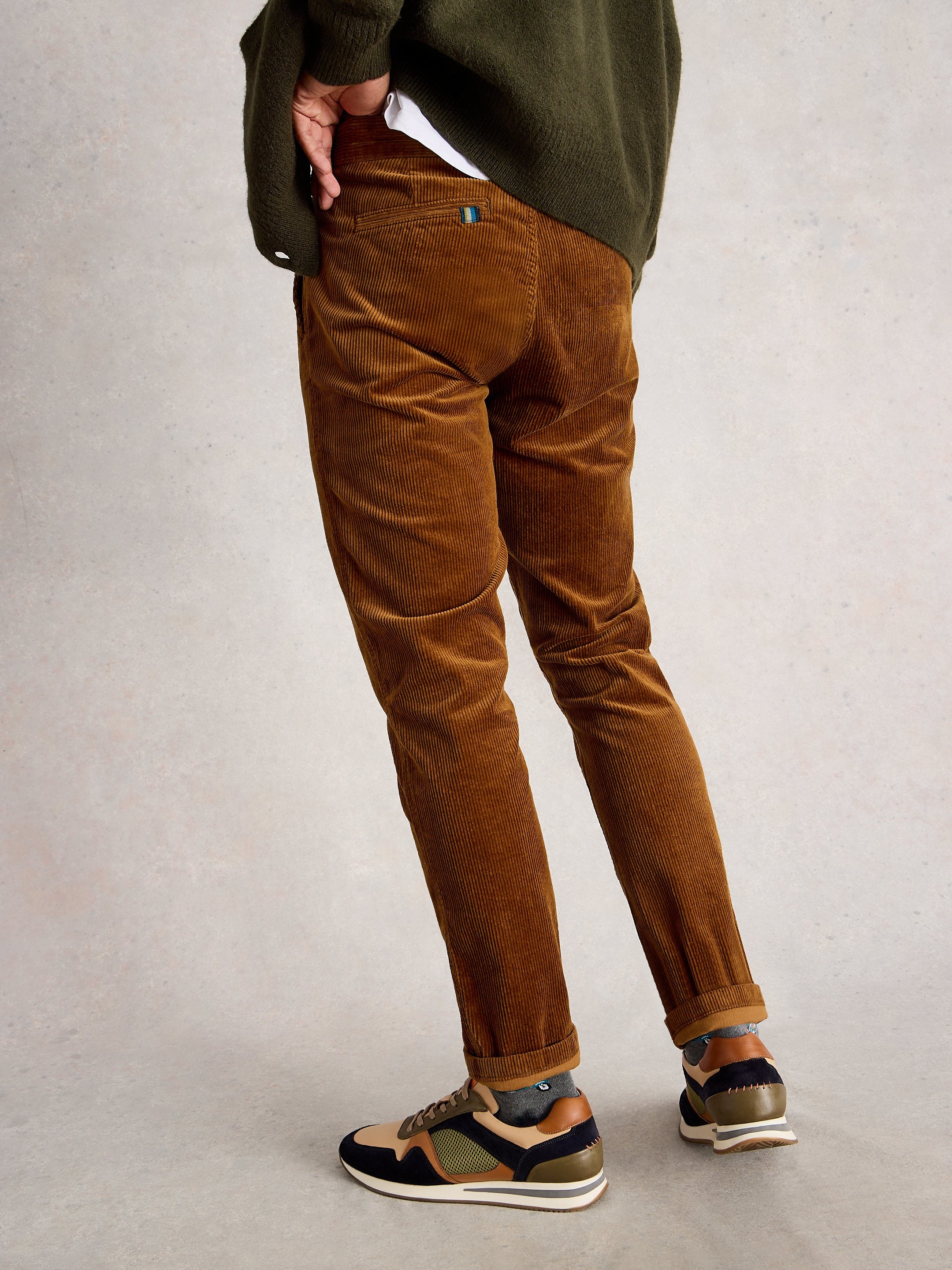 Brown corduroy pants worn by a person on a plain background