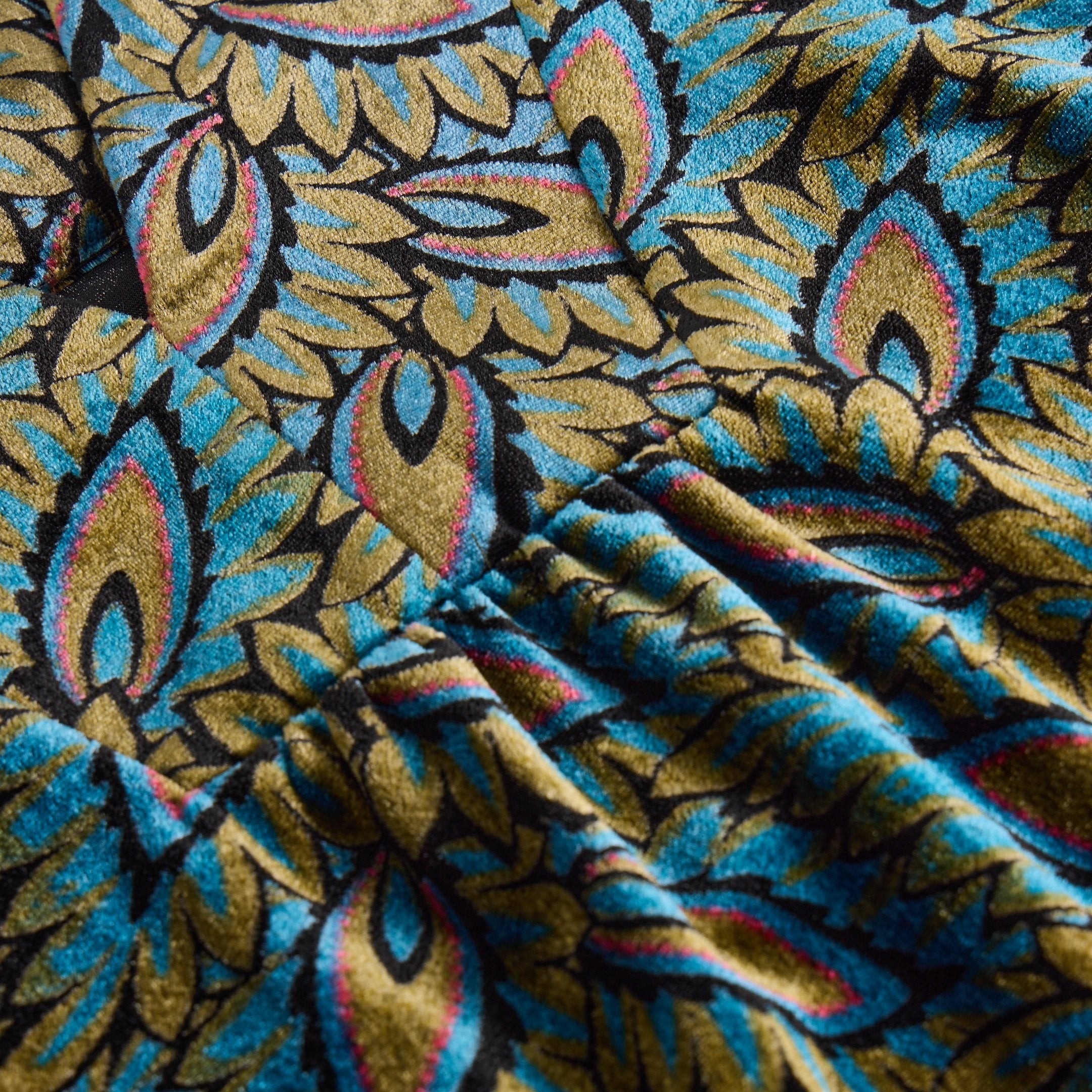 Close-up of teal and olive green velvet fabric with a paisley-like pattern. The texture is visible.