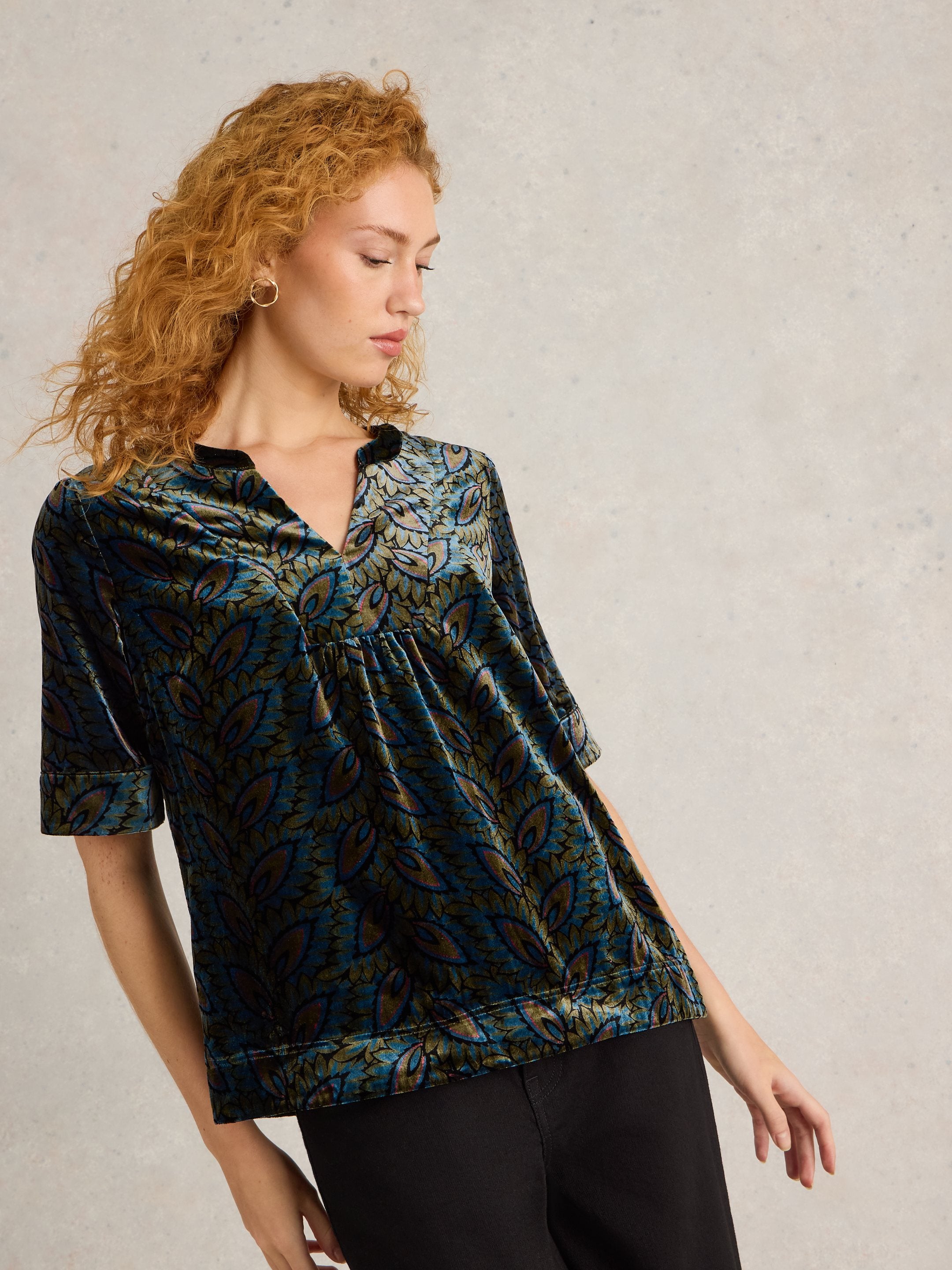 Teal velvet top with a V-neck and short sleeves, featuring a dark teal and olive green leaf print.