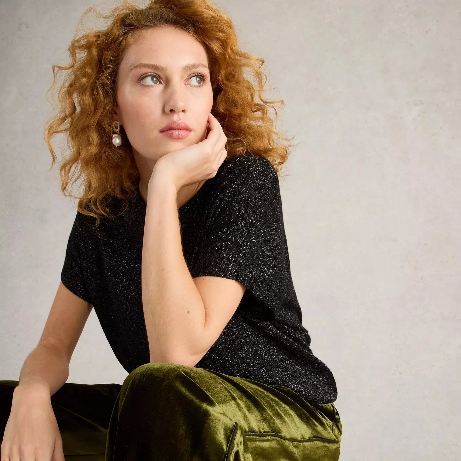 Black glitter short-sleeved top paired with olive green velvet pants.