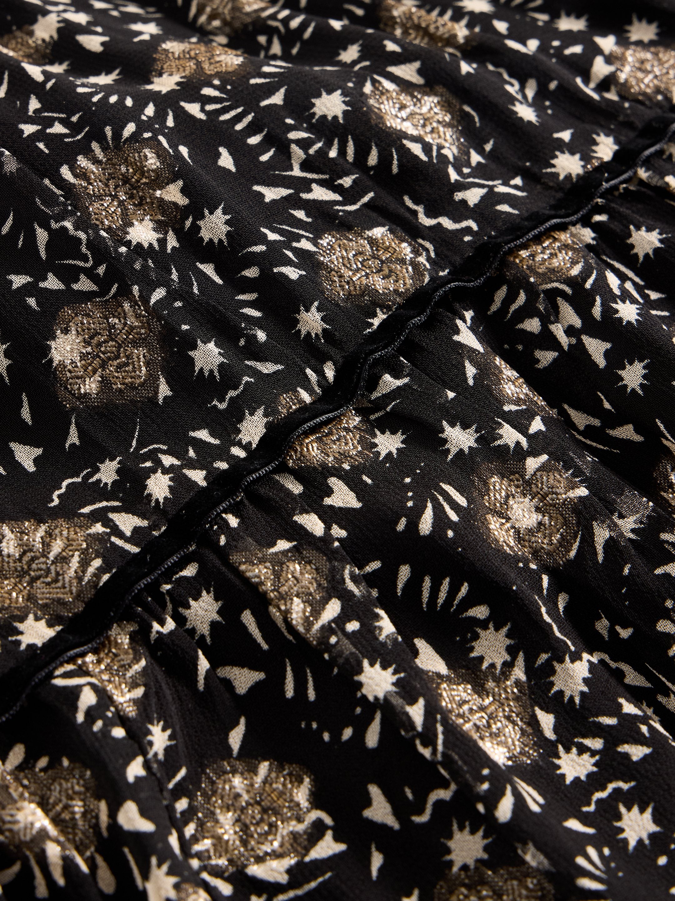 Close-up of black fabric with a metallic gold and off-white star and abstract print.