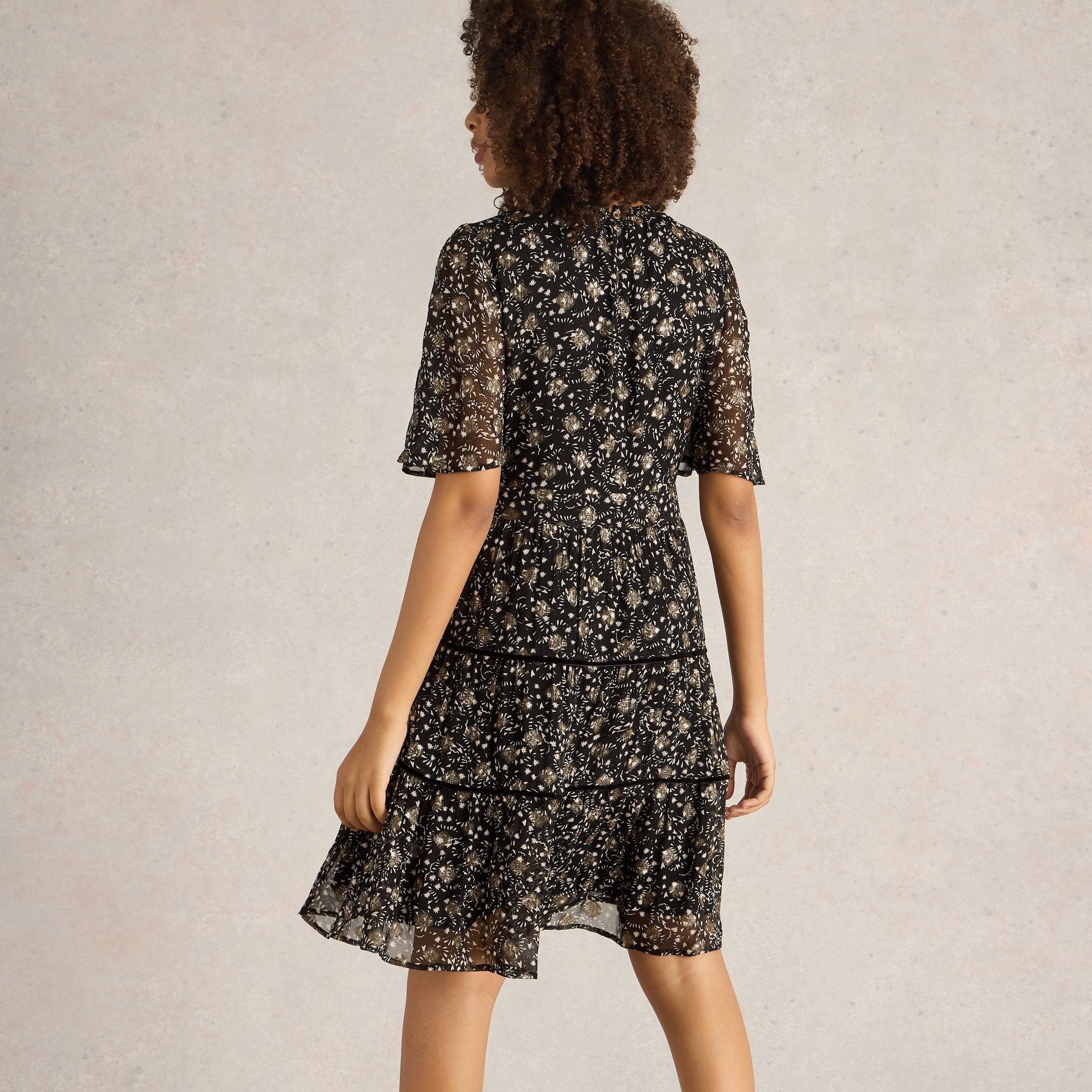 Black tiered mini dress with gold star print and short sleeves.