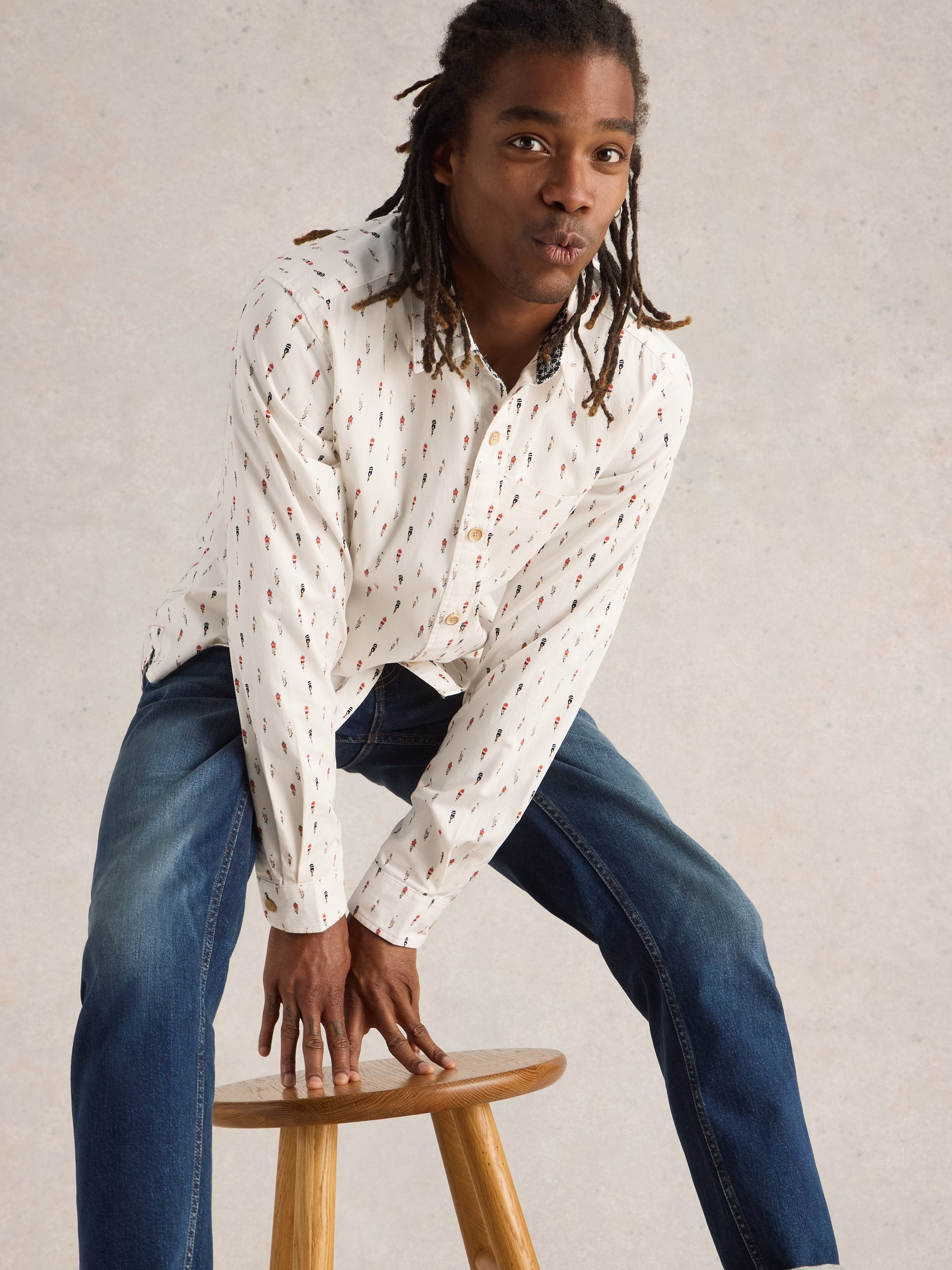 Off-white long-sleeve shirt with a repeating pattern of small figures, modeled by a person with long dark hair.