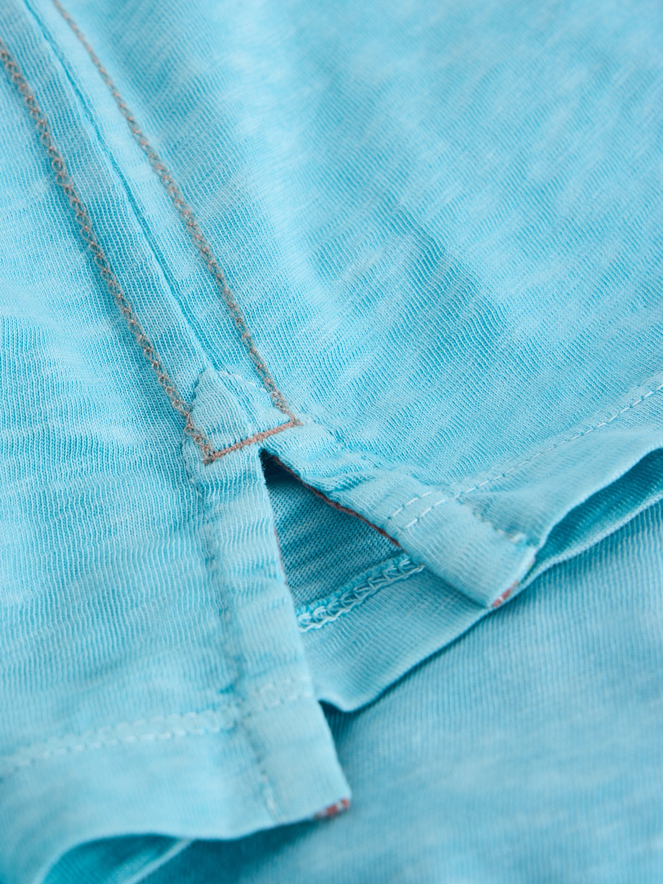 Close-up of light blue fabric with detailed stitching, showing texture and a side seam.