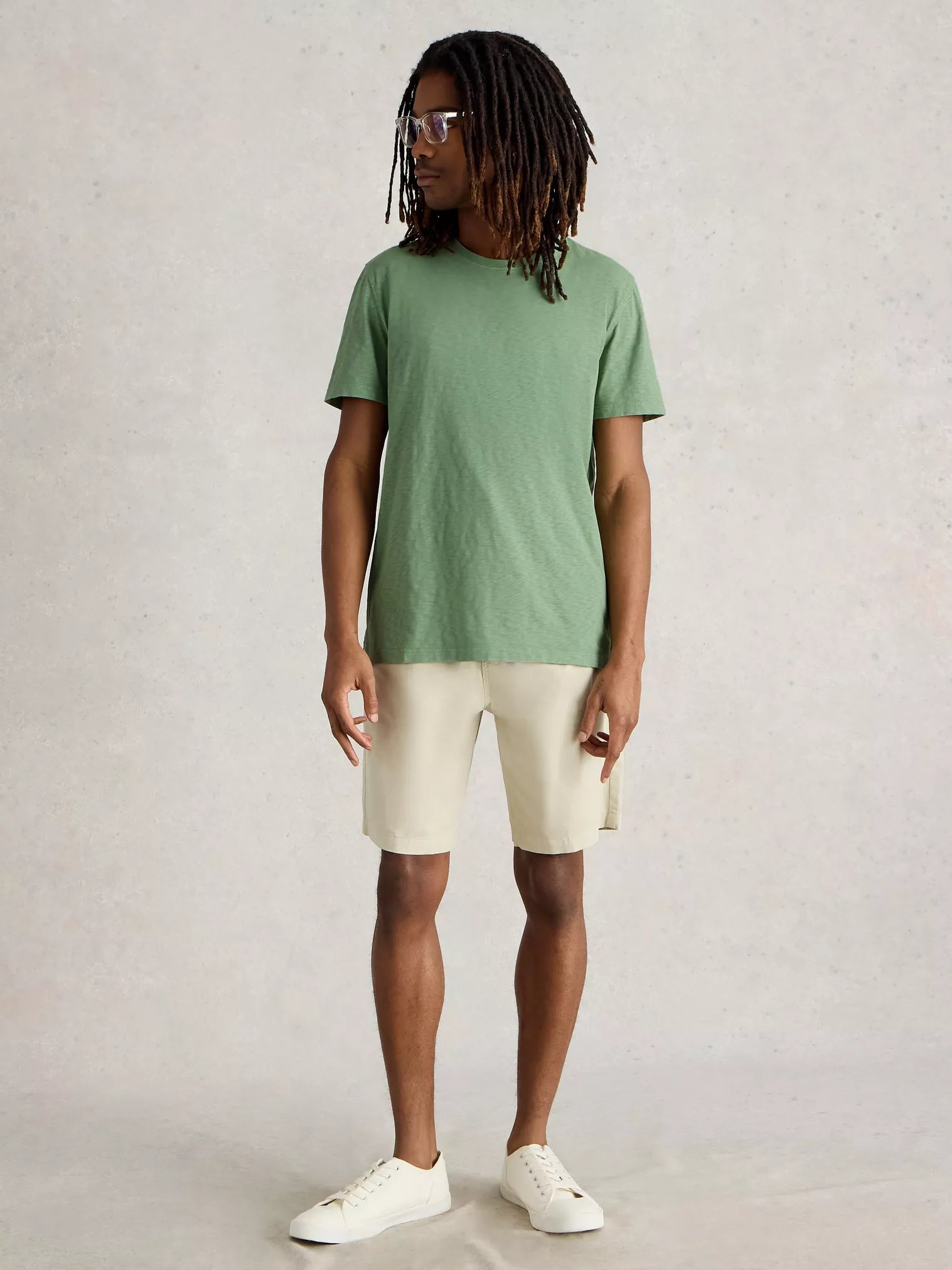 Sage green crew neck t-shirt and light beige shorts on a male model.