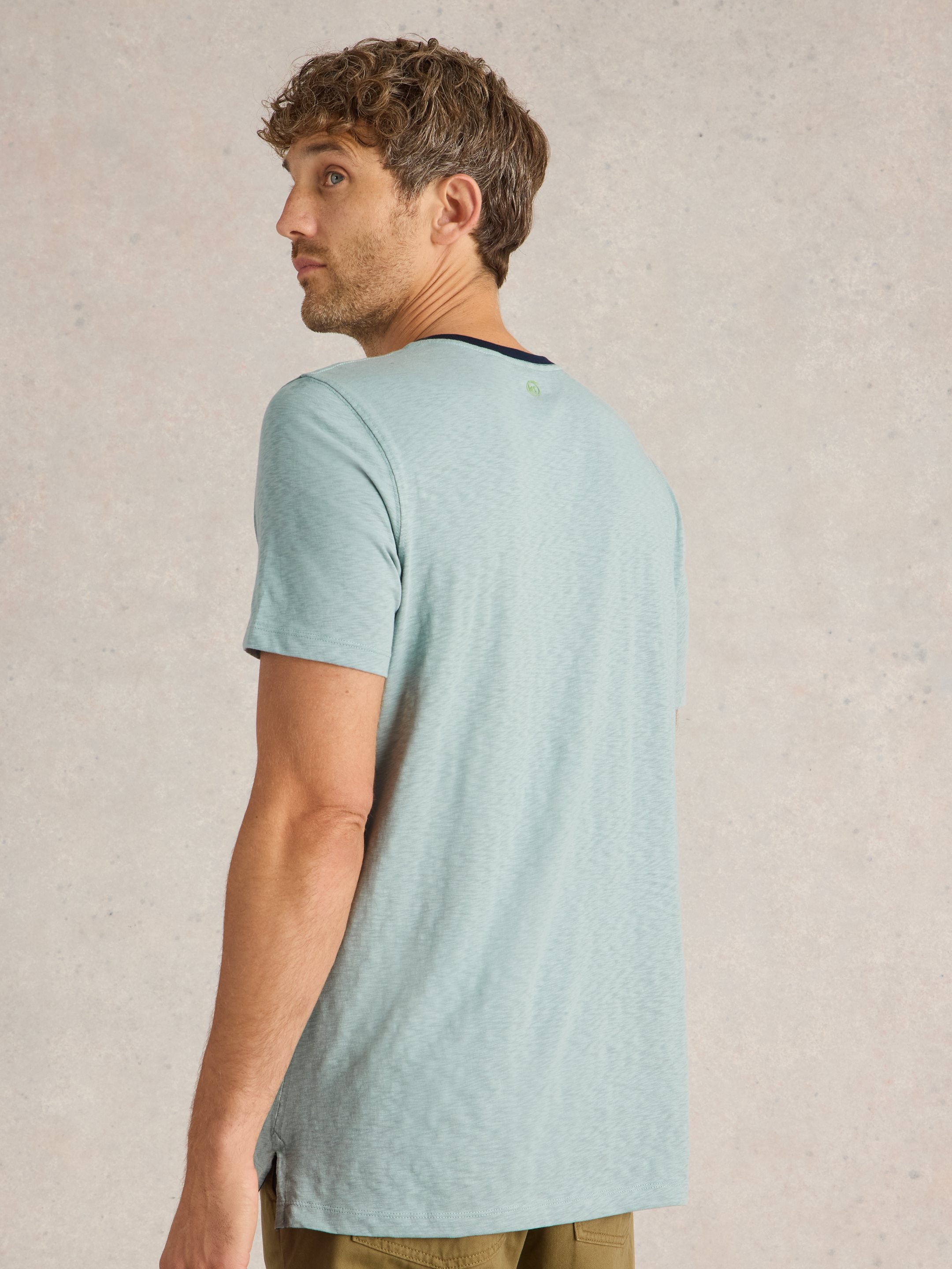 Light teal short-sleeve crew neck t-shirt, viewed from the back, featuring a subtle textured fabric and a small, barely