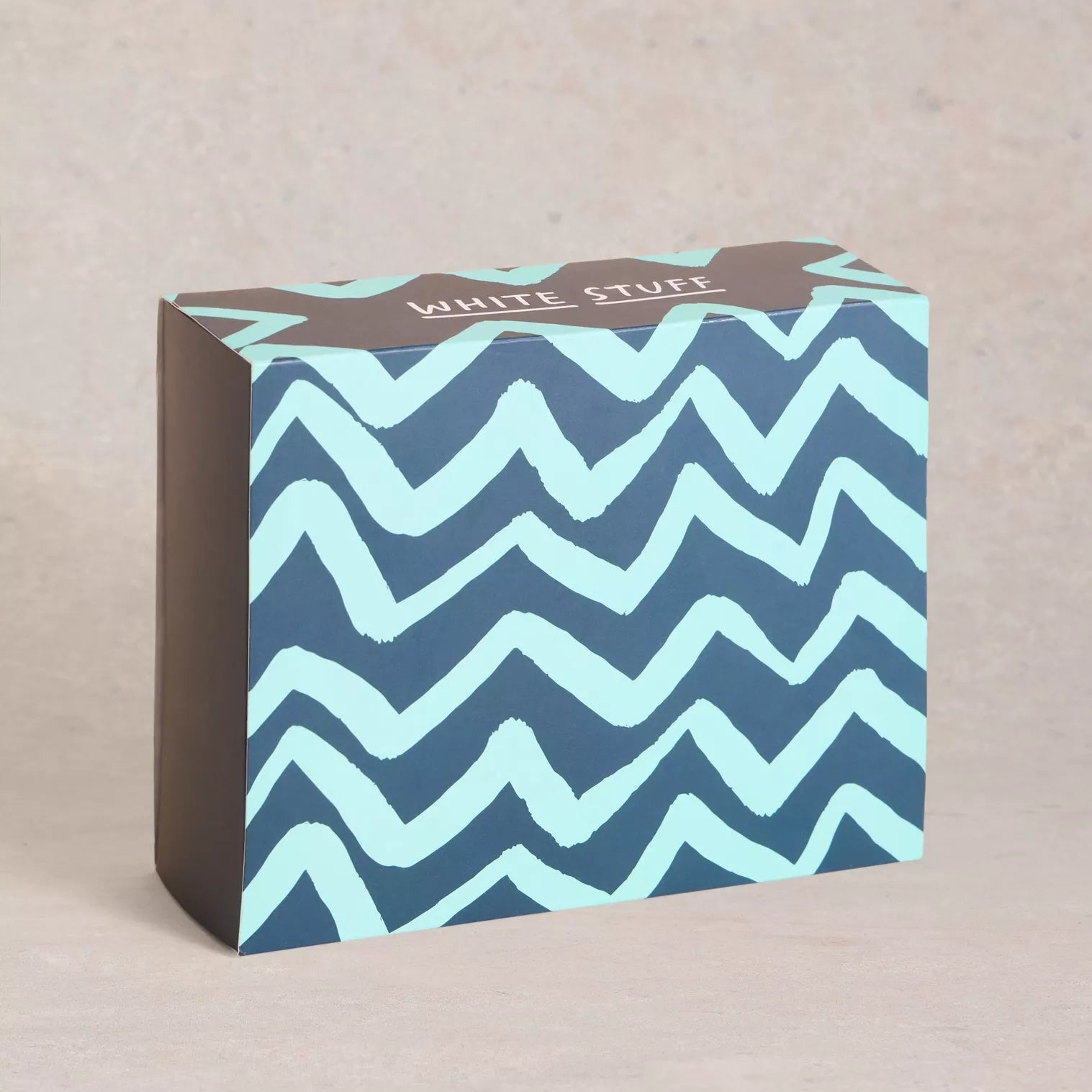 Rectangular box with a teal and dark blue zig-zag pattern, and "White Stuff" text on the top.