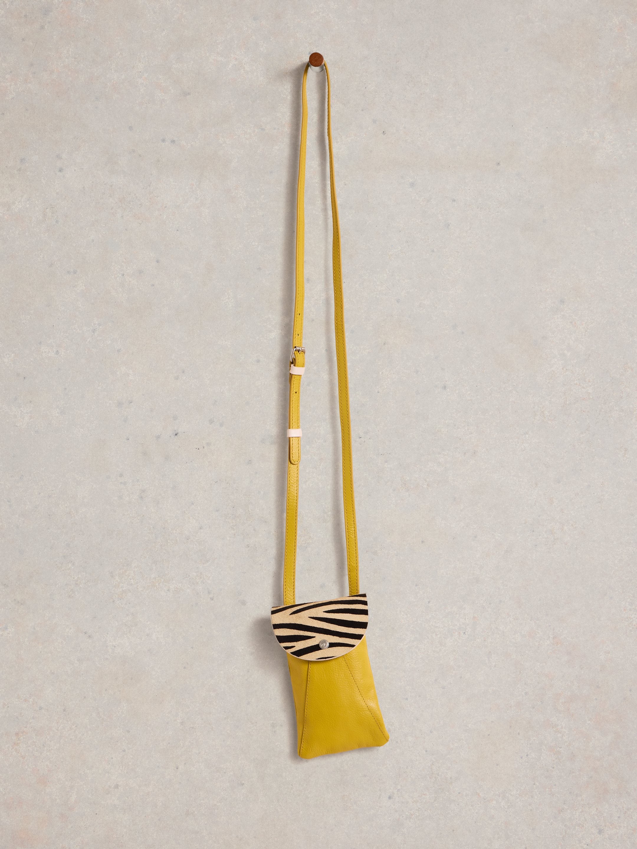 Mustard yellow leather crossbody bag with a zebra-striped flap.