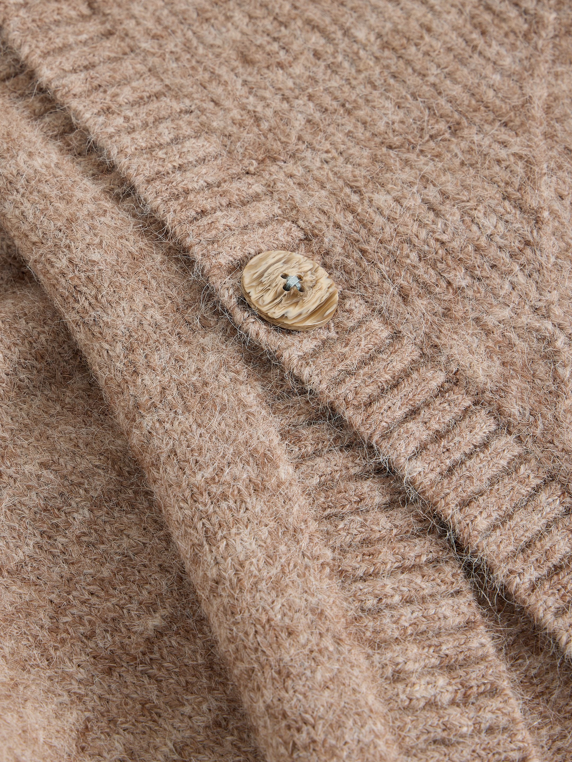 Close-up of a beige textured fabric with a button