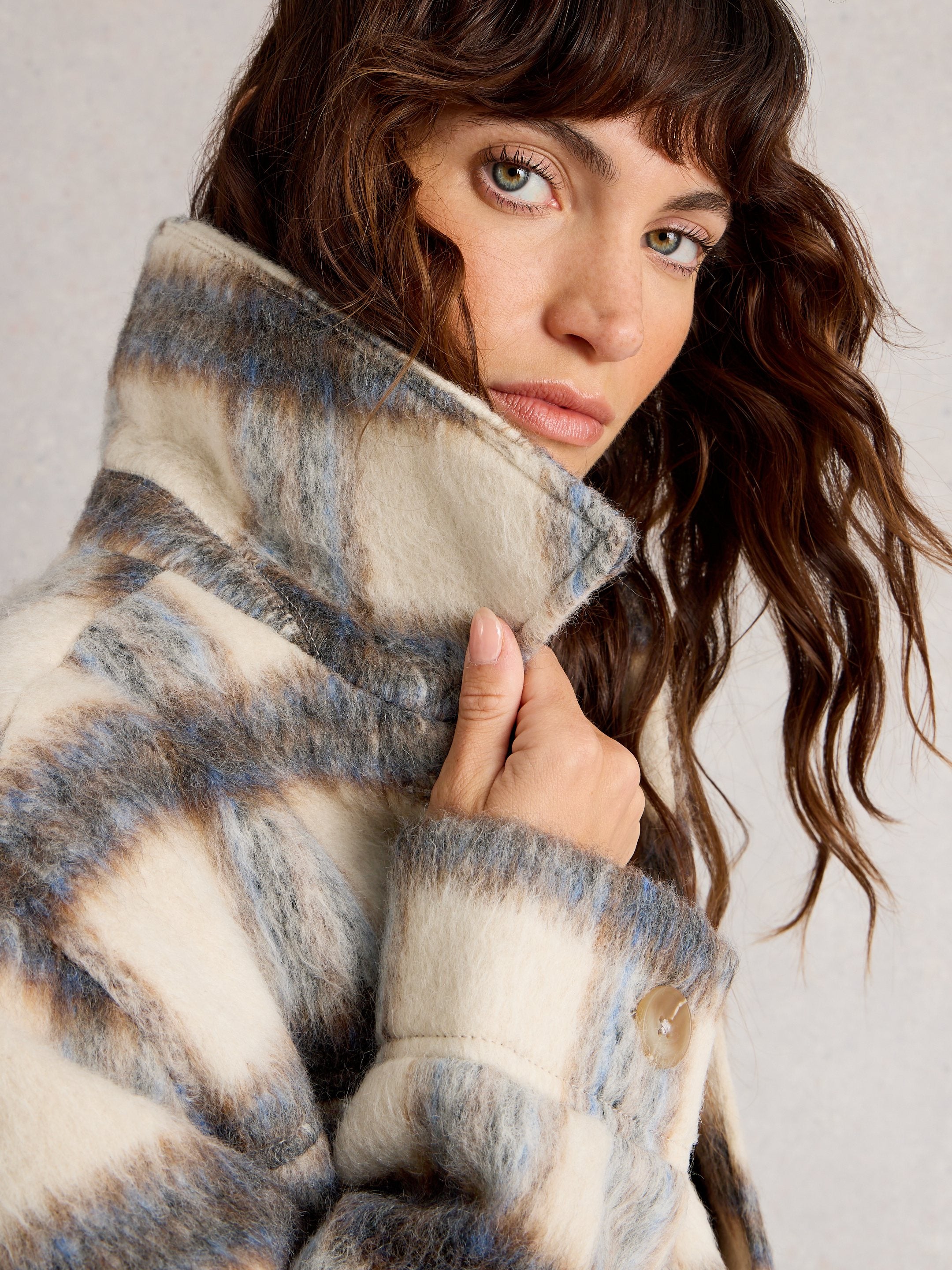 Woman wearing a patterned coat with a neutral background
