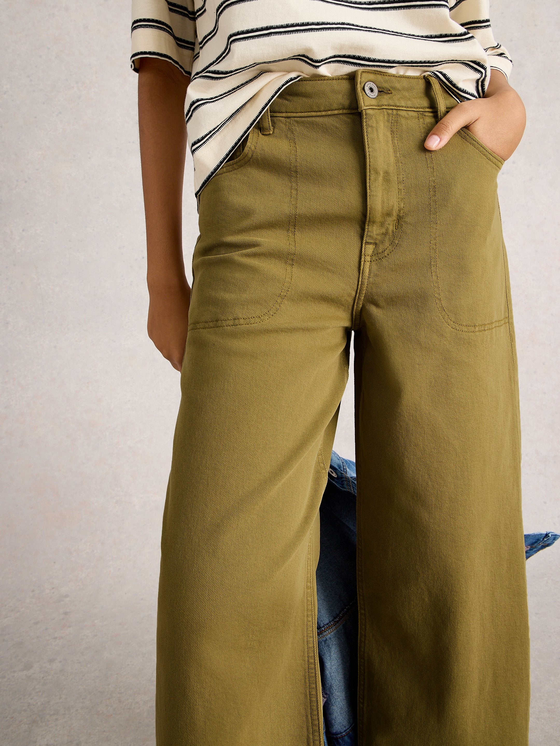 Person wearing olive green pants with a neutral background