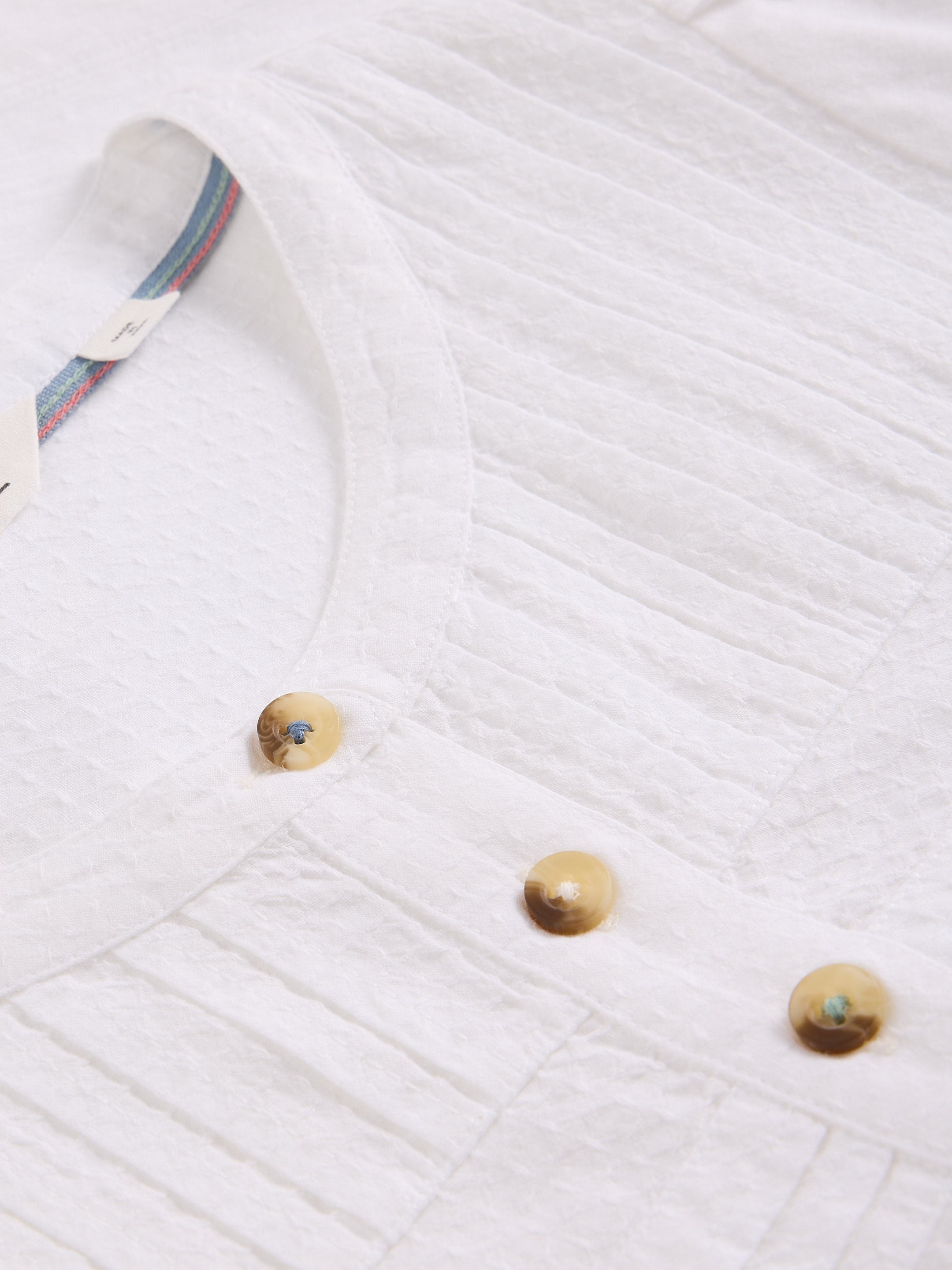 Close-up of a white textured fabric with wooden buttons on a white background
