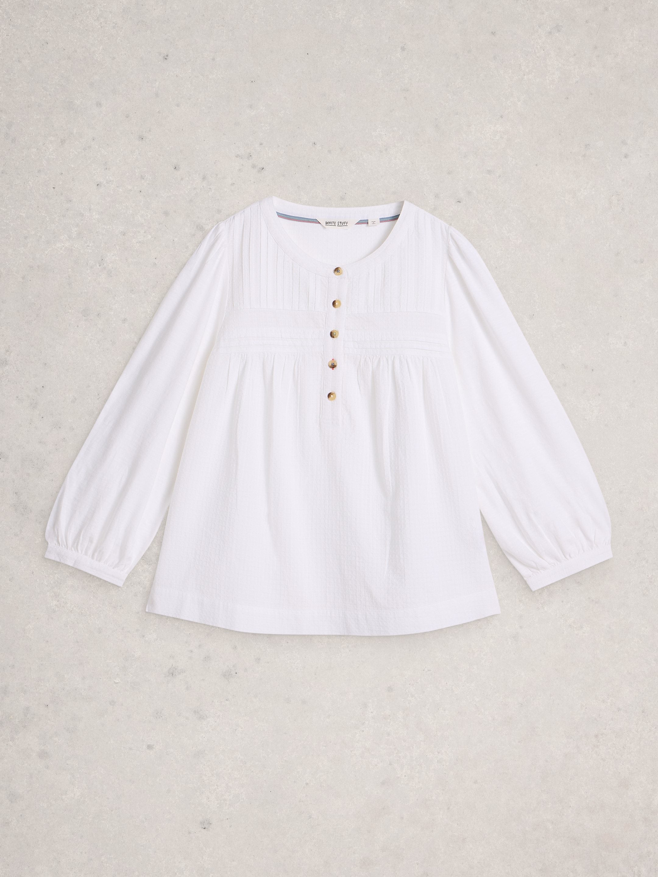 White blouse with long sleeves on a light beige background