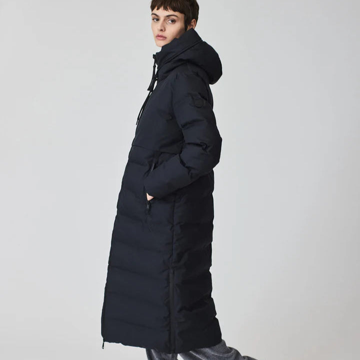 Person wearing a long black puffer coat on a plain background