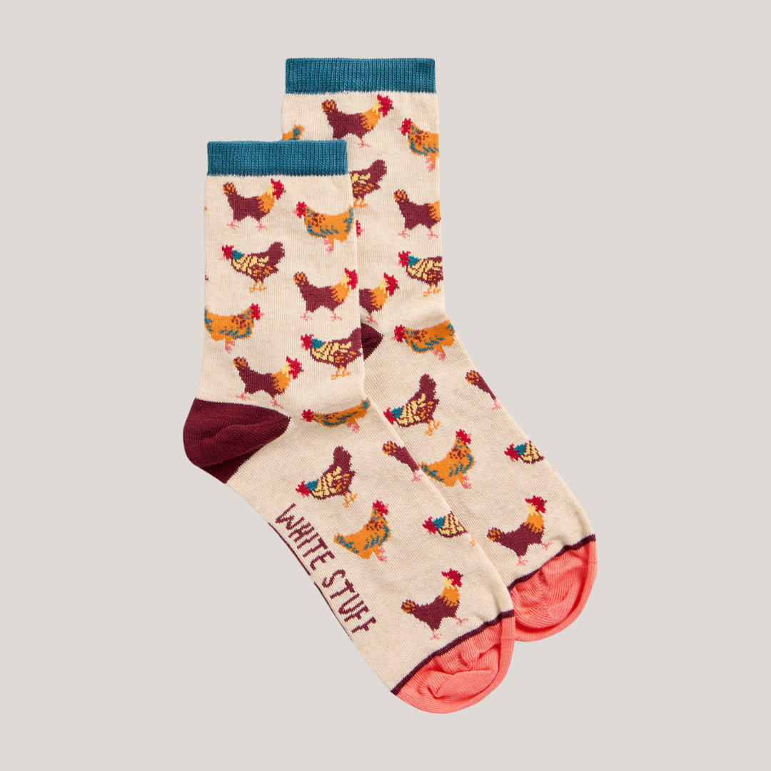 Pair of cream ankle socks featuring a repeating pattern of colorful chickens. "White Stuff" is subtly printed on one sock.