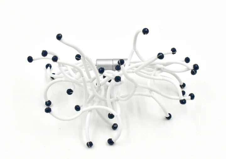 White sculptural piece with numerous curving stems tipped with dark blue beads, connected by a central silver clasp.